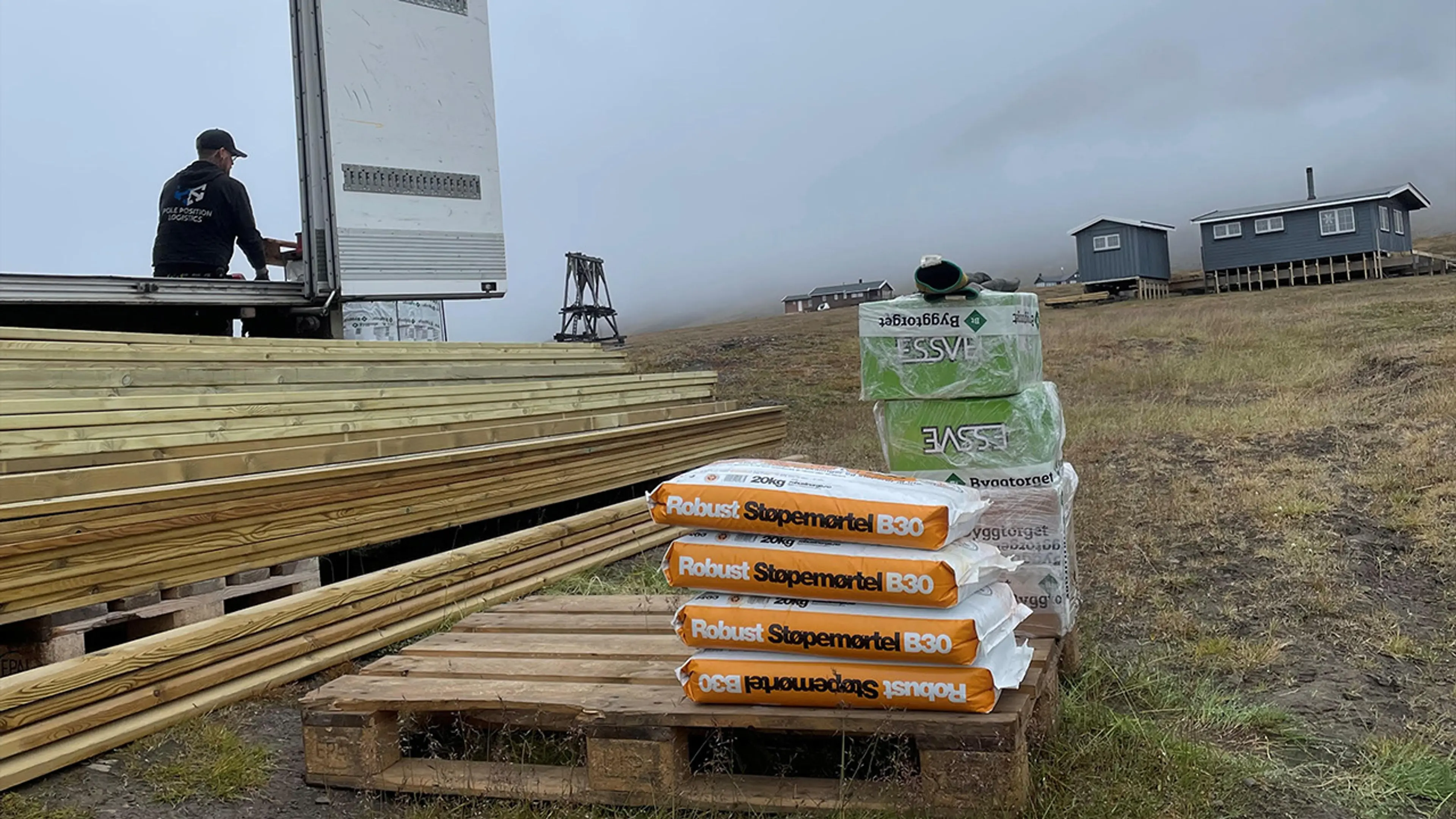 materiell, mørtel og skruer foran en hytte på Svalbard