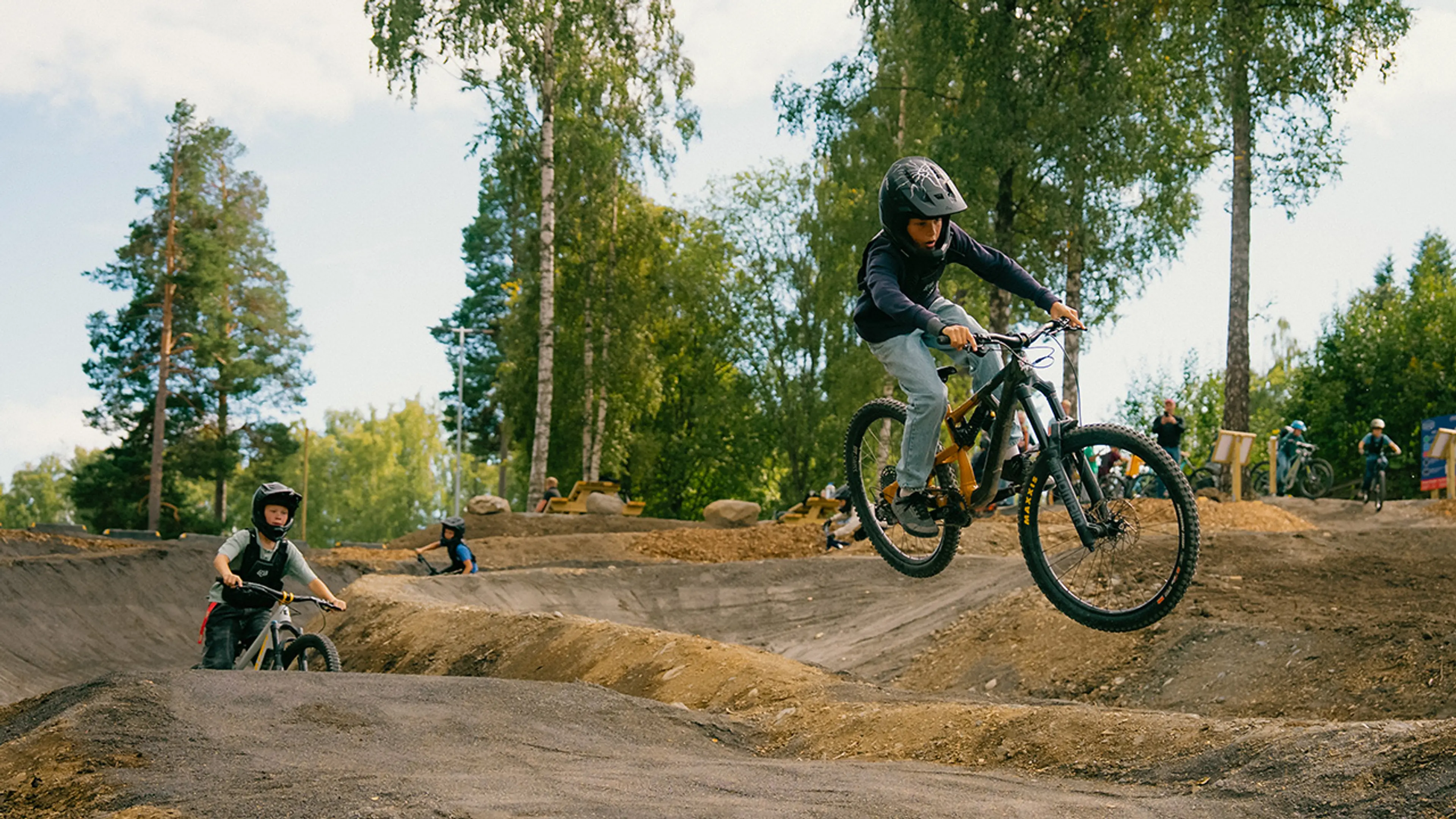 Gutter som sykler i sykkelpark og hopper over hinder.