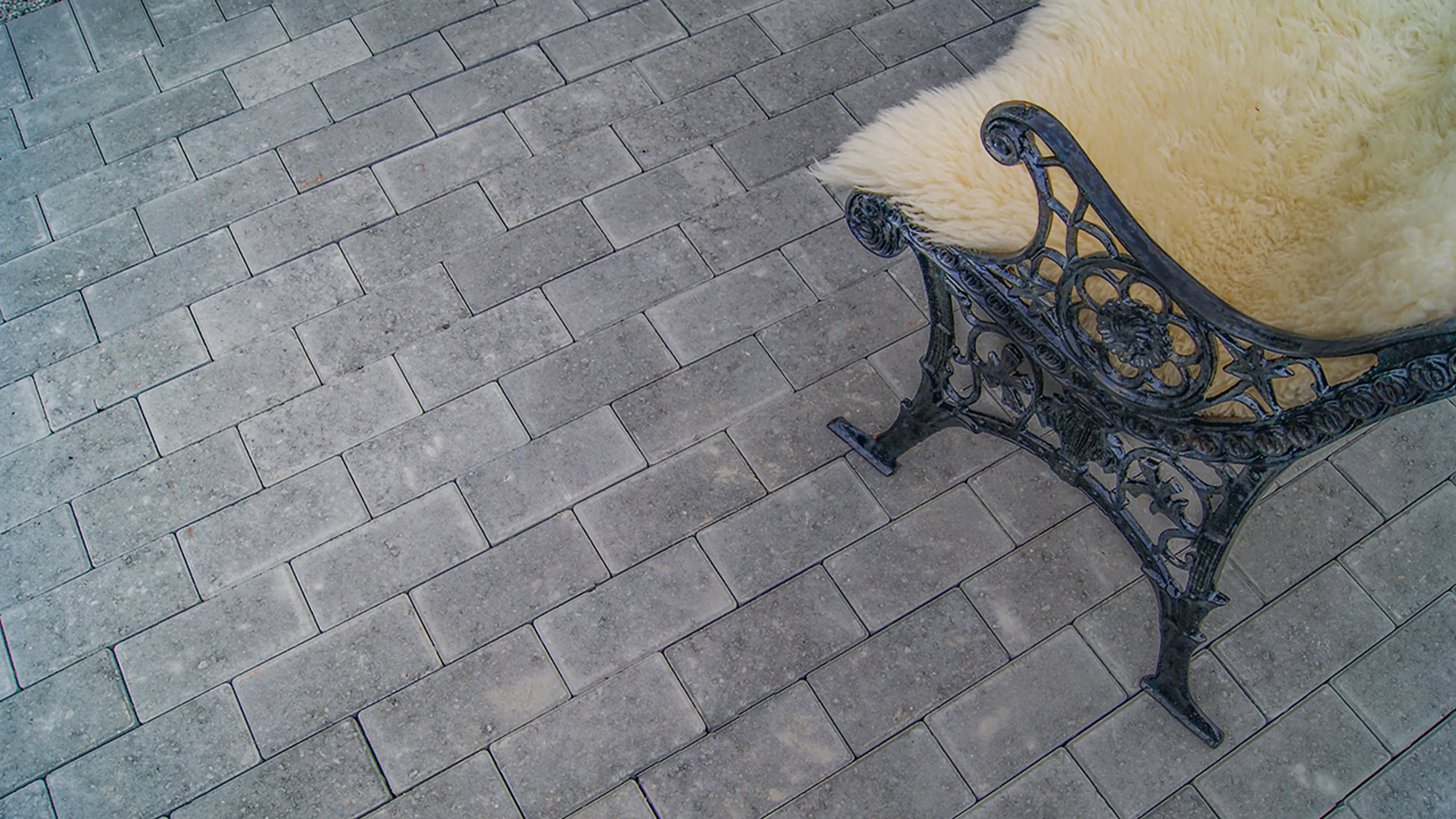 Parkstein belegningsstein og benk i smijern med skinnfell.