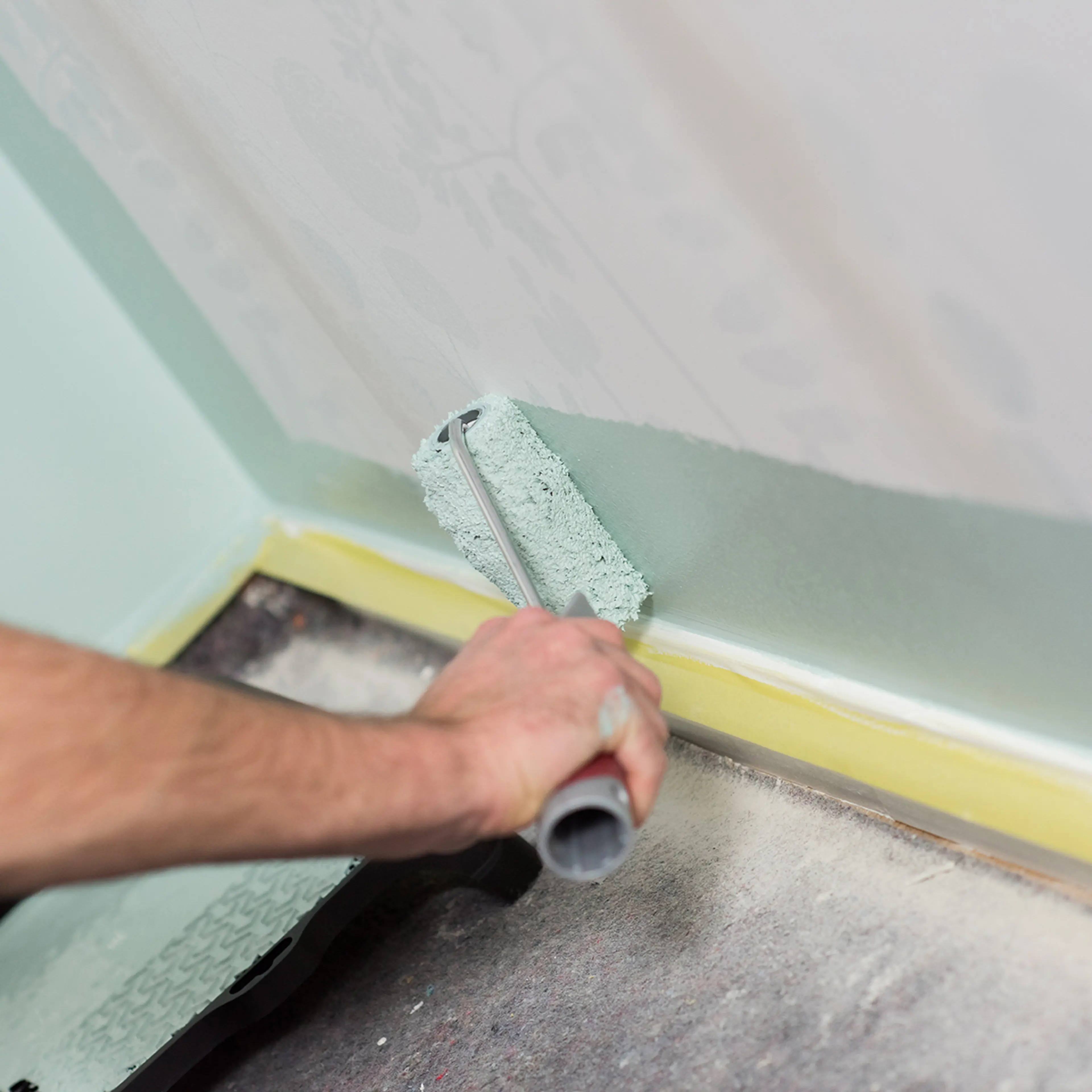 Mann som maler over tapet med malerulle.