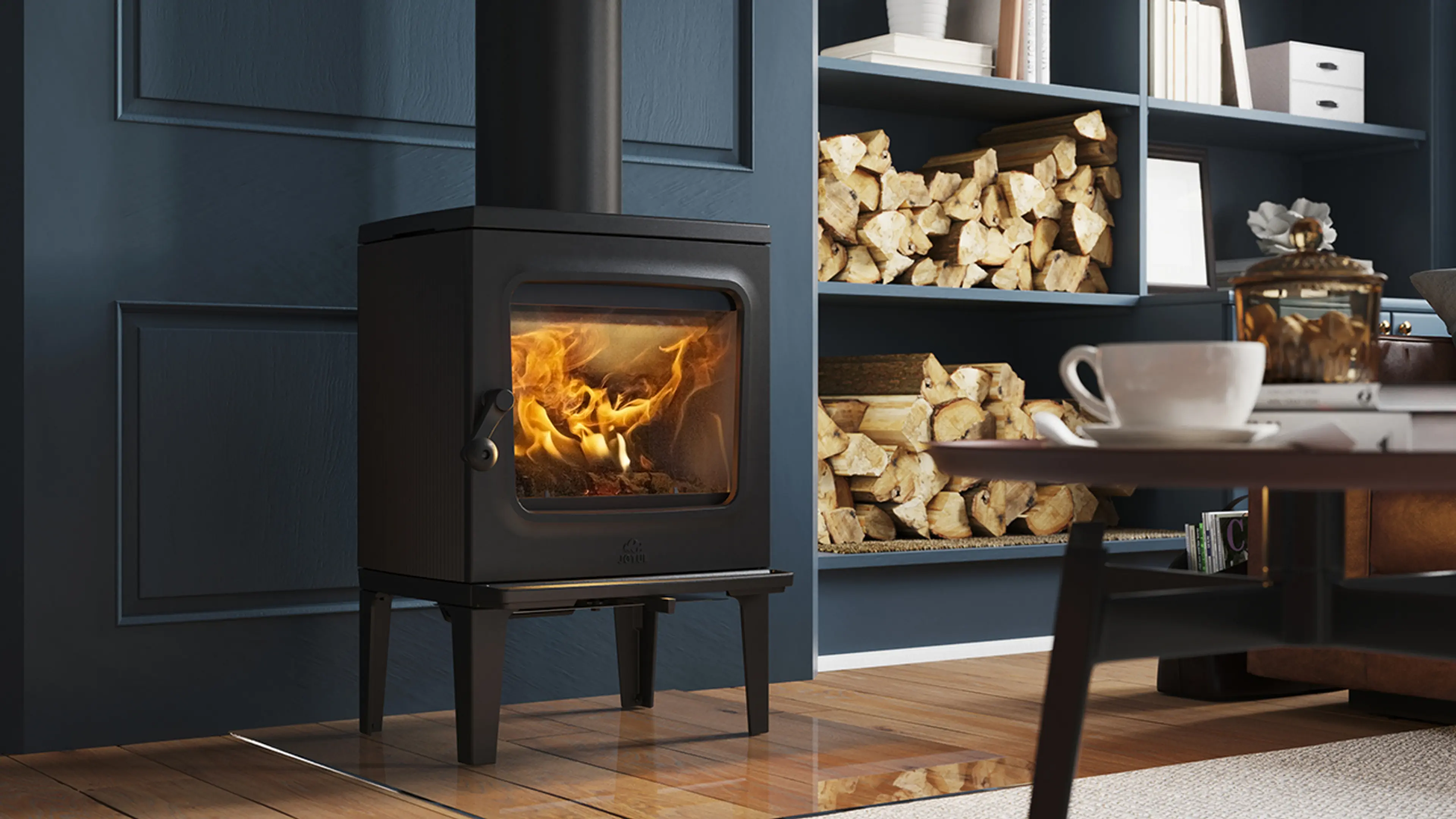 Liten klassisk støpejernsovn i blå stue med innebygget bokhylle med ved i nederste hyllene.