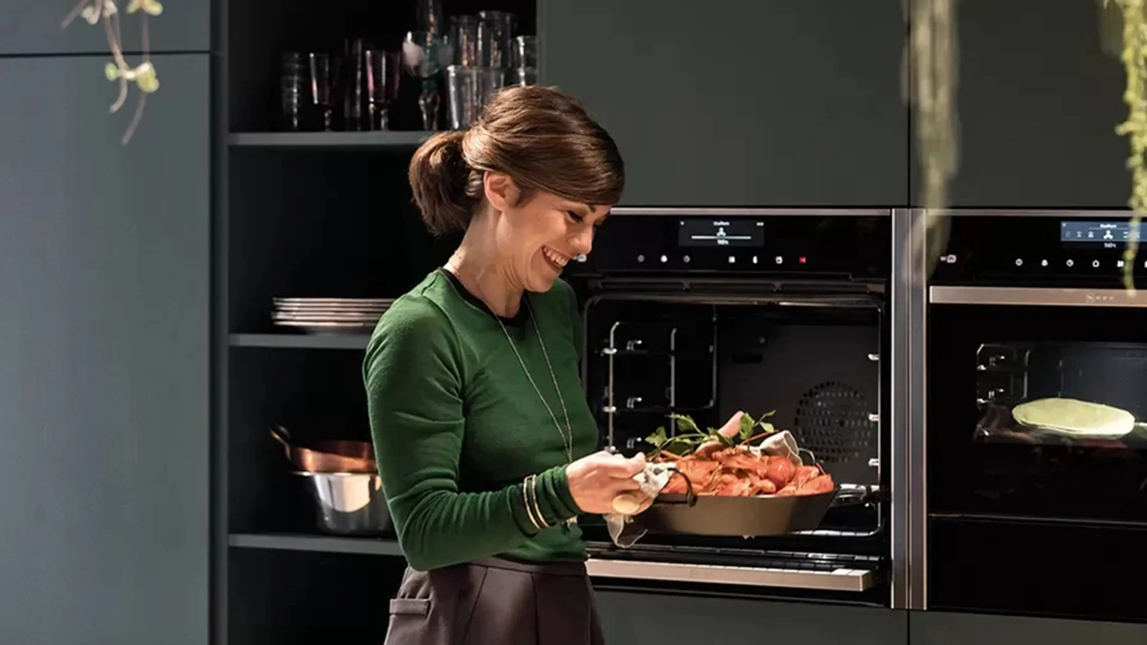 Dame tar ut mat fra stekeovn integrert i kjøkkenskap.