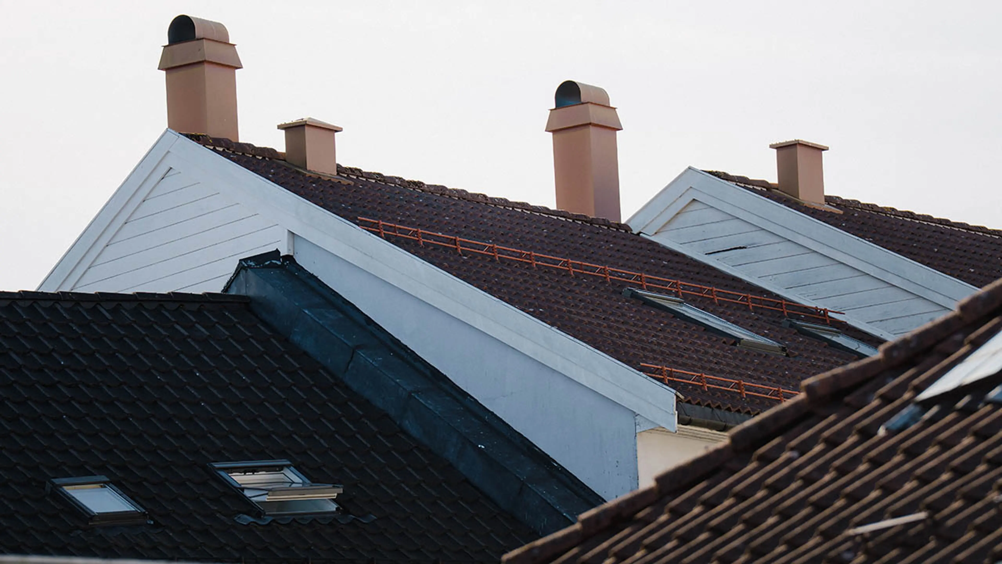 Toppen av hvite trehus med rød og svarte takstein på taket.