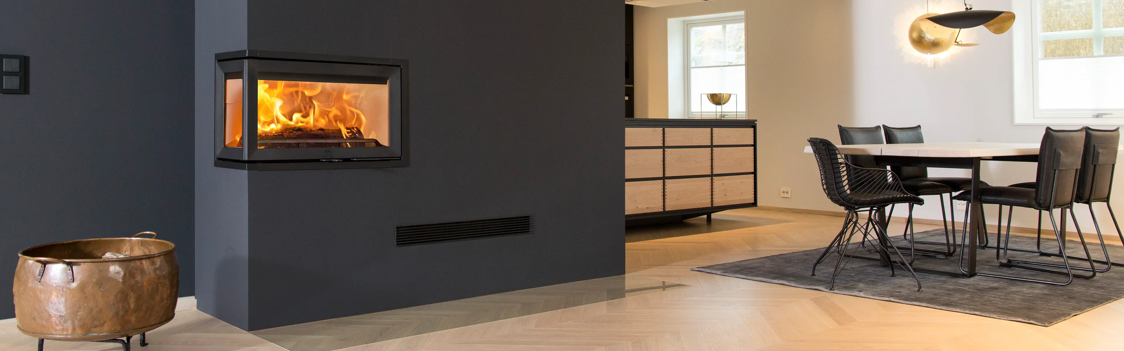 Mørk peis i åpen stue-kjøkken-løsning.