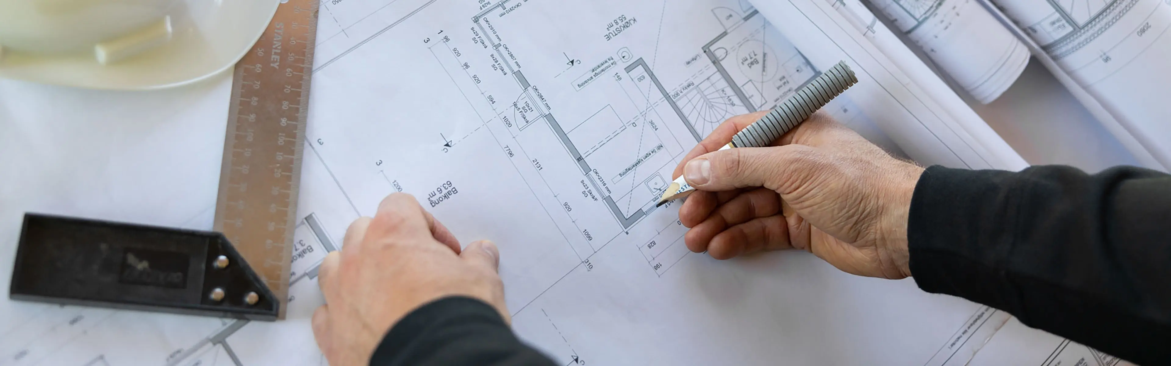 en mann ser på byggetegninger som ligger på et bord