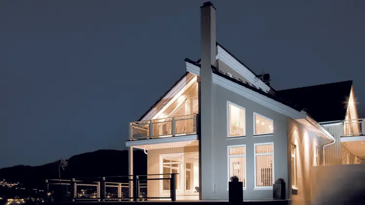 Hvitthus med store pvc-vinduer sett utenfra om kvelden.
