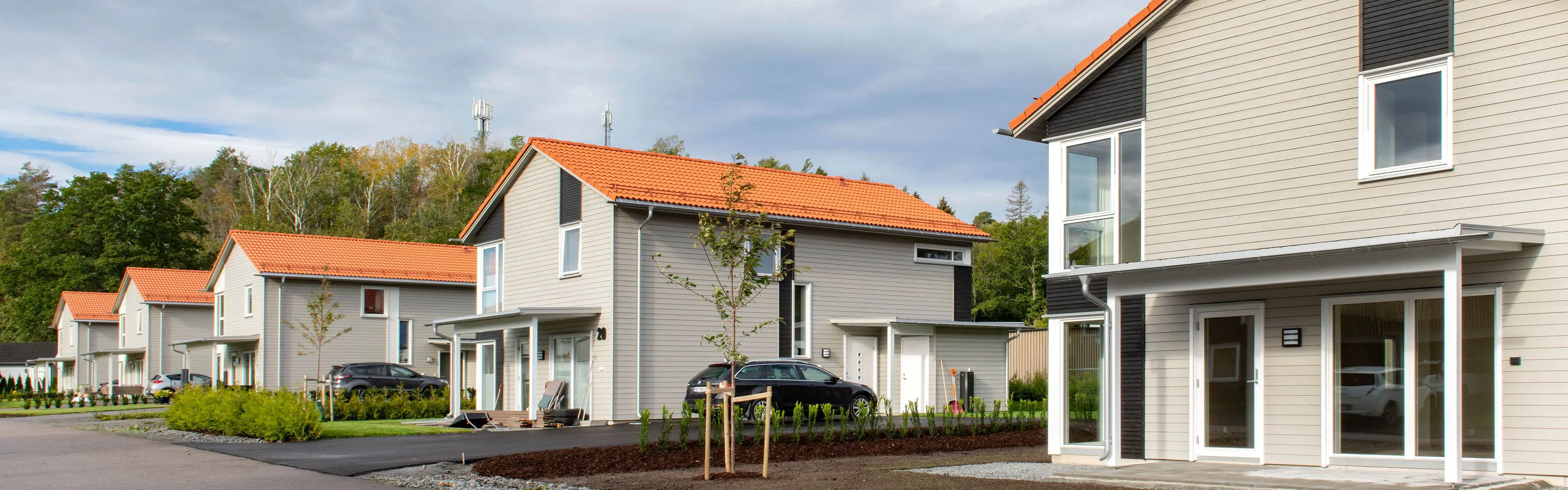 Moderne rekkehus i en idyllisk gate, som alle har ferdigmalt kledning.