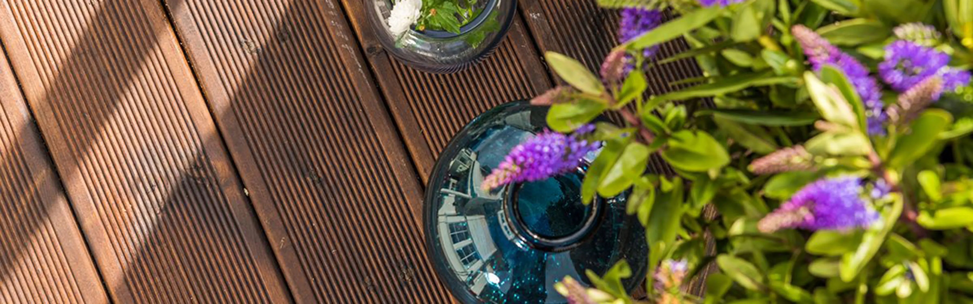 Nærbilde av brunoljet Duo terrassebord med sommerblomster på