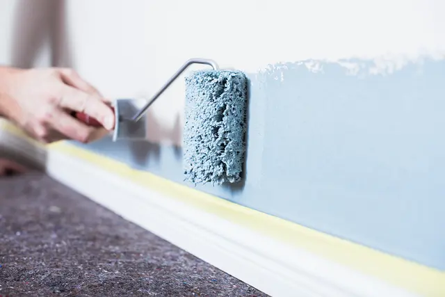 En vegg inne males lyseblå med rulle fra Jordan