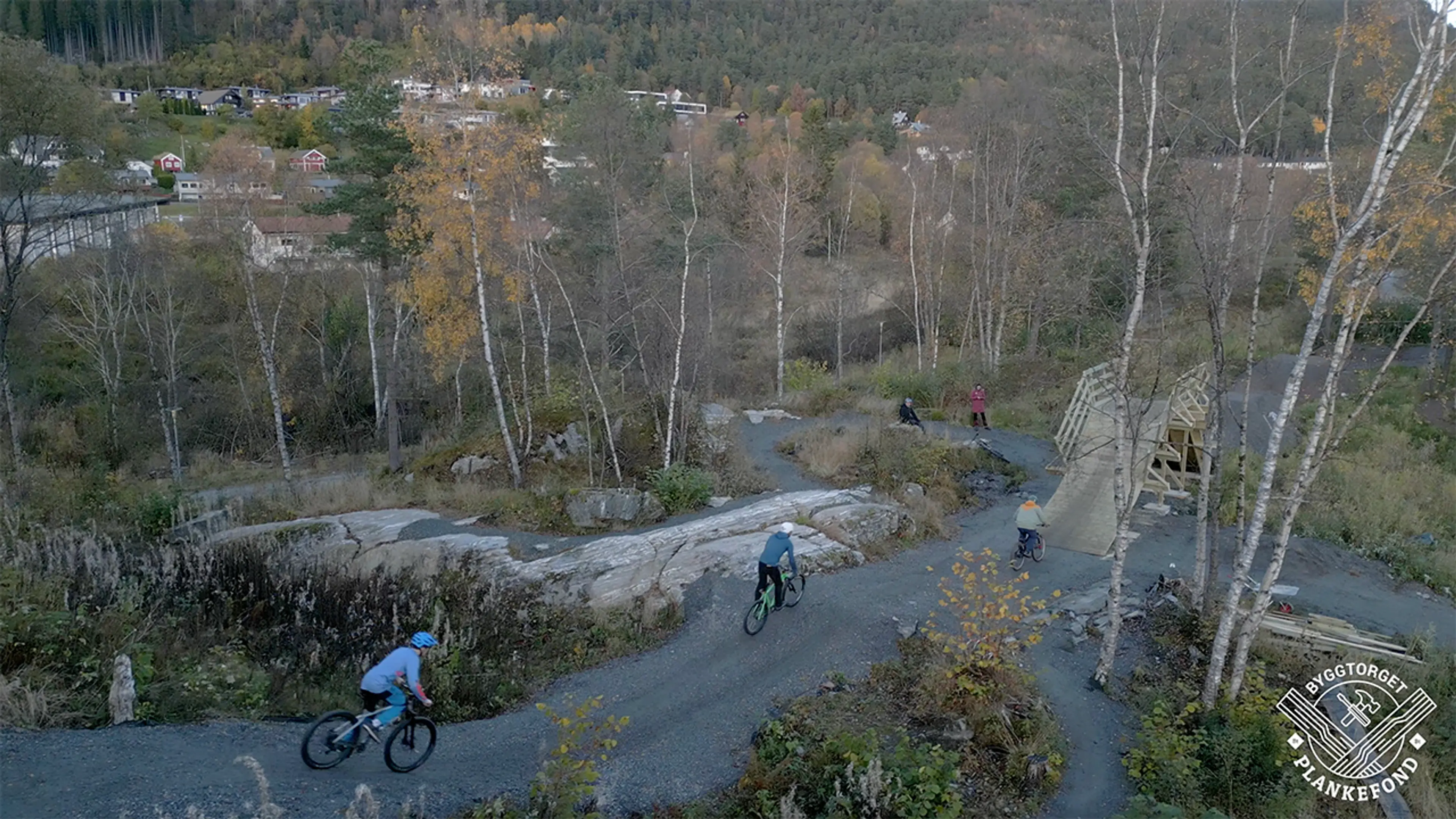 Tre personer som sykler på sykkelbro i terrengsykkelpark.