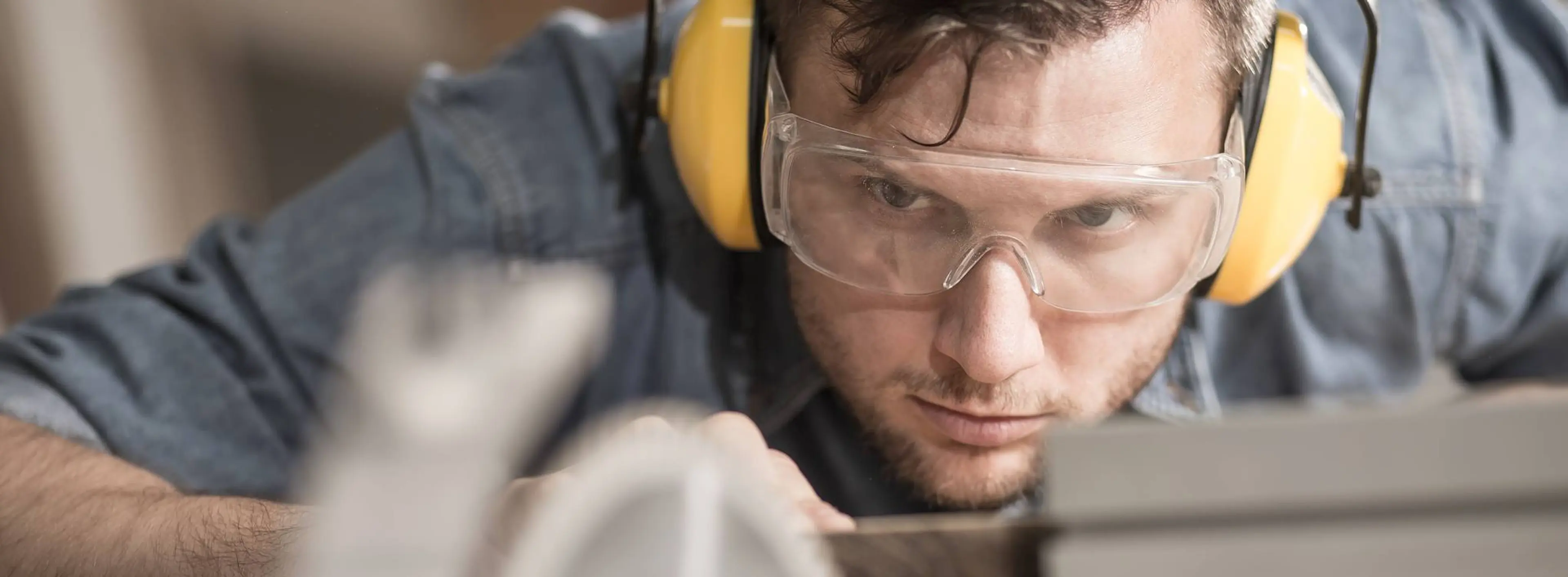 Mann med gule hørselvern og vernebriller