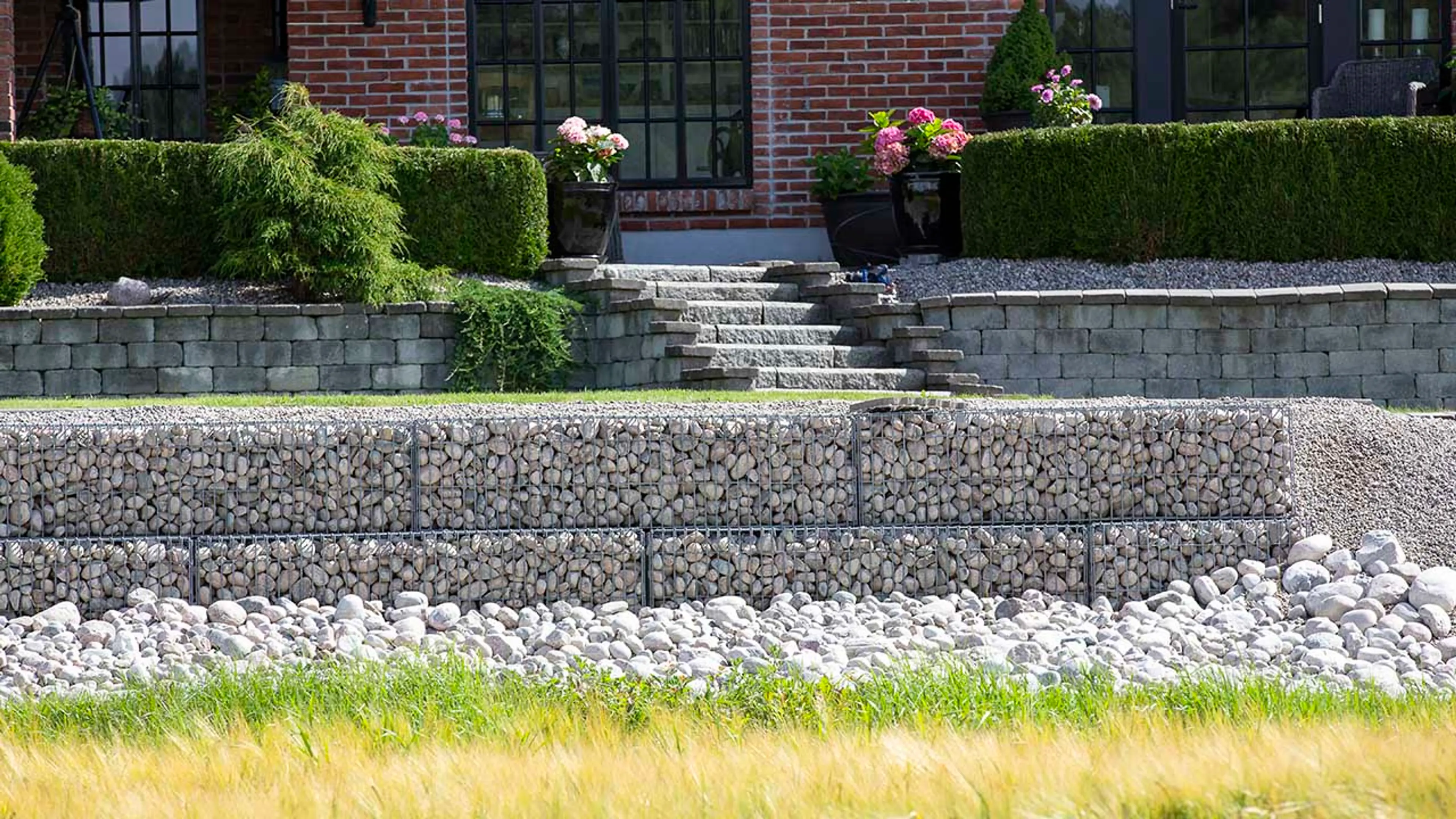 To ulike billige støttemurer i hage foran hus.