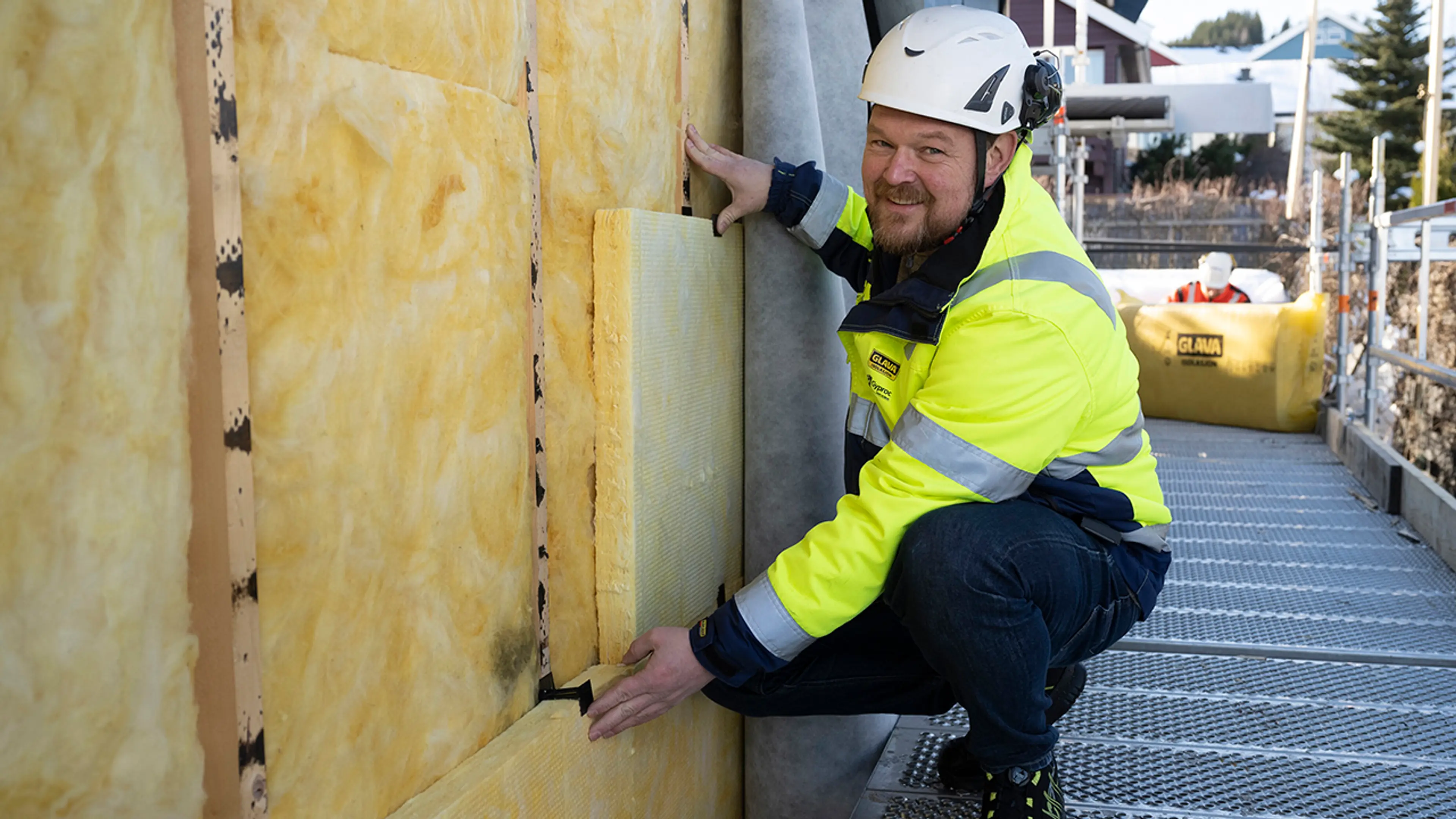 Håndverker som etterisolerer yttervegg med Glava isolasjon.