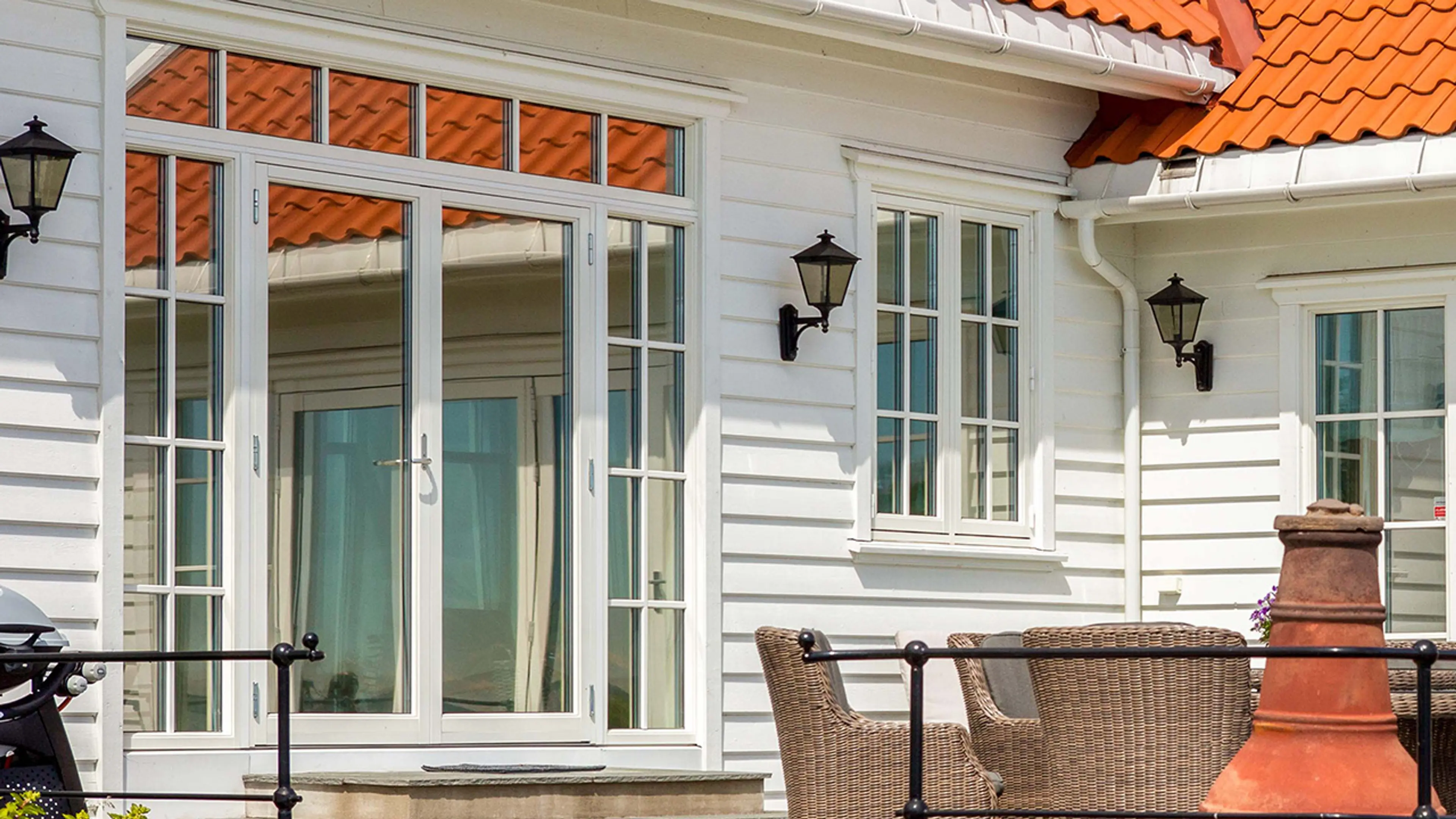 Hvitt hus med dobbel verandadør i helglass og sidefelt med sprosser.