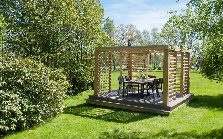 pergola i ubehandlet treverk bygget på en frittstående platting i hagen