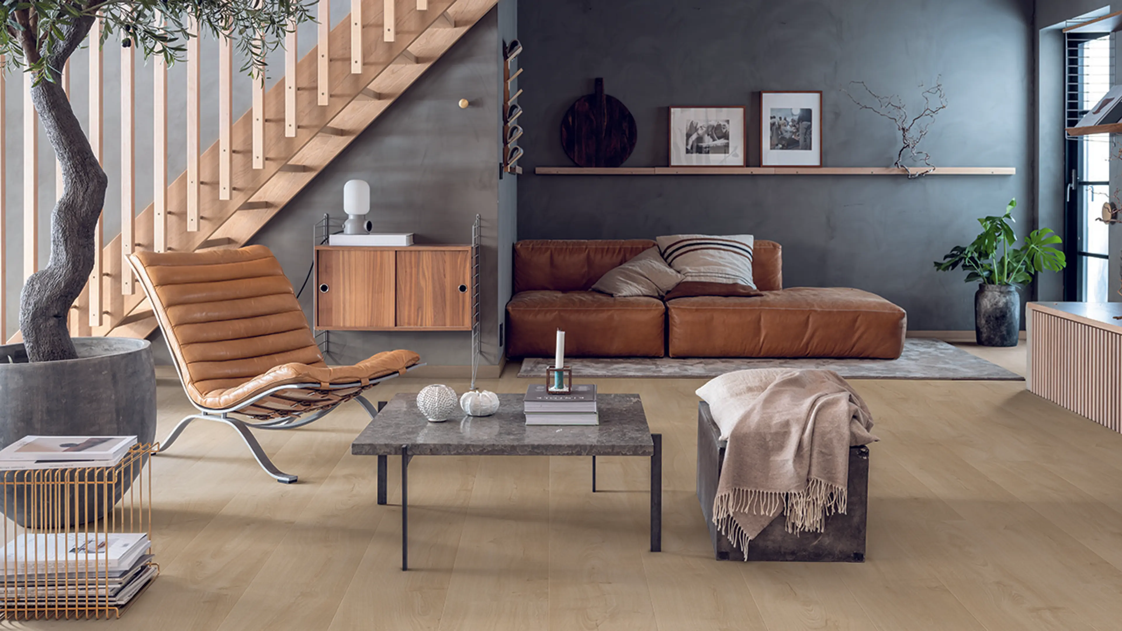 Moderne stue med skinnmøbler og steindetaljer med Trondheim laminatgulv fra Pergo.