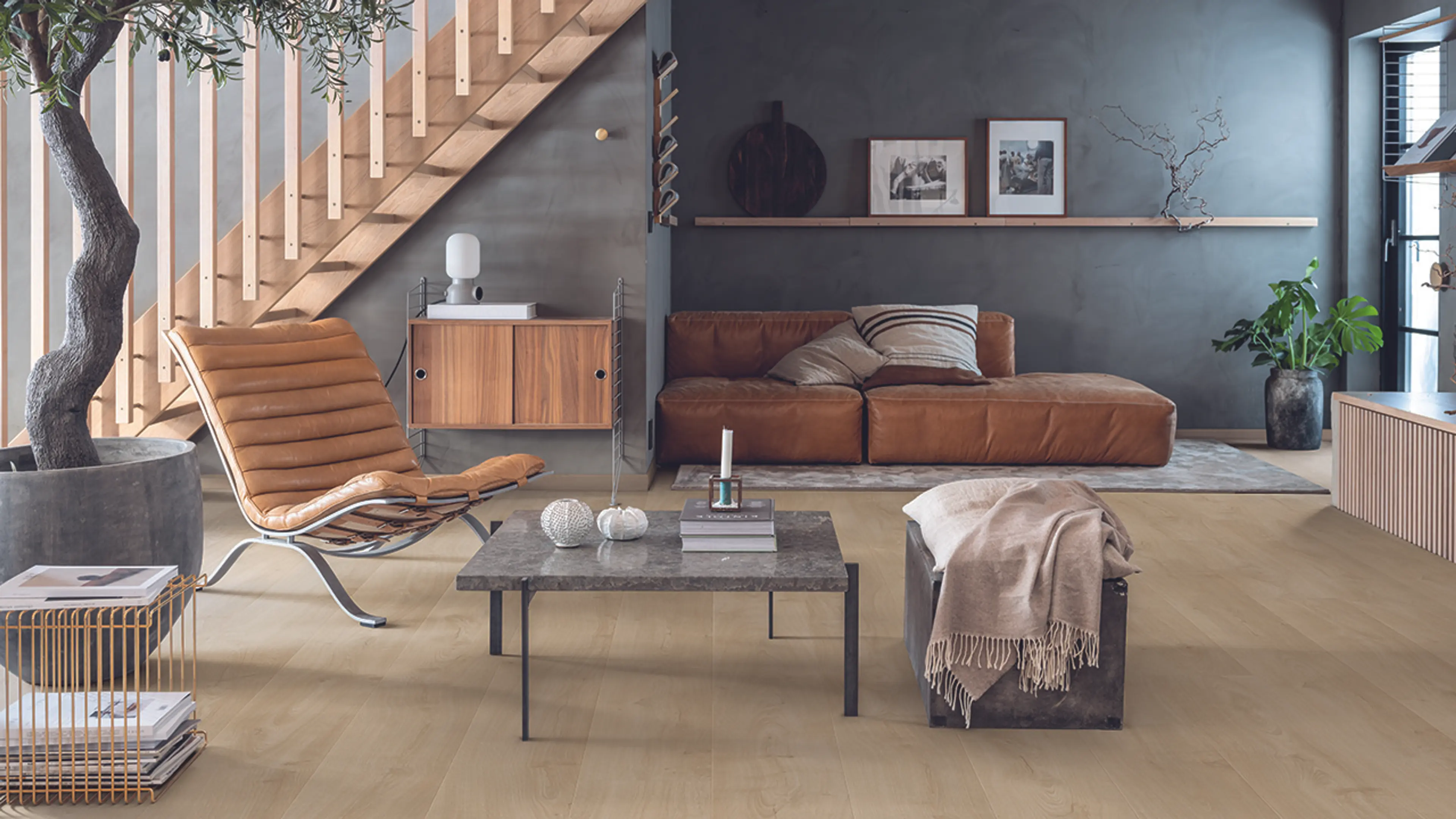 Moderne stue med skinnmøbler og steindetaljer med Trondheim laminatgulv fra Pergo.