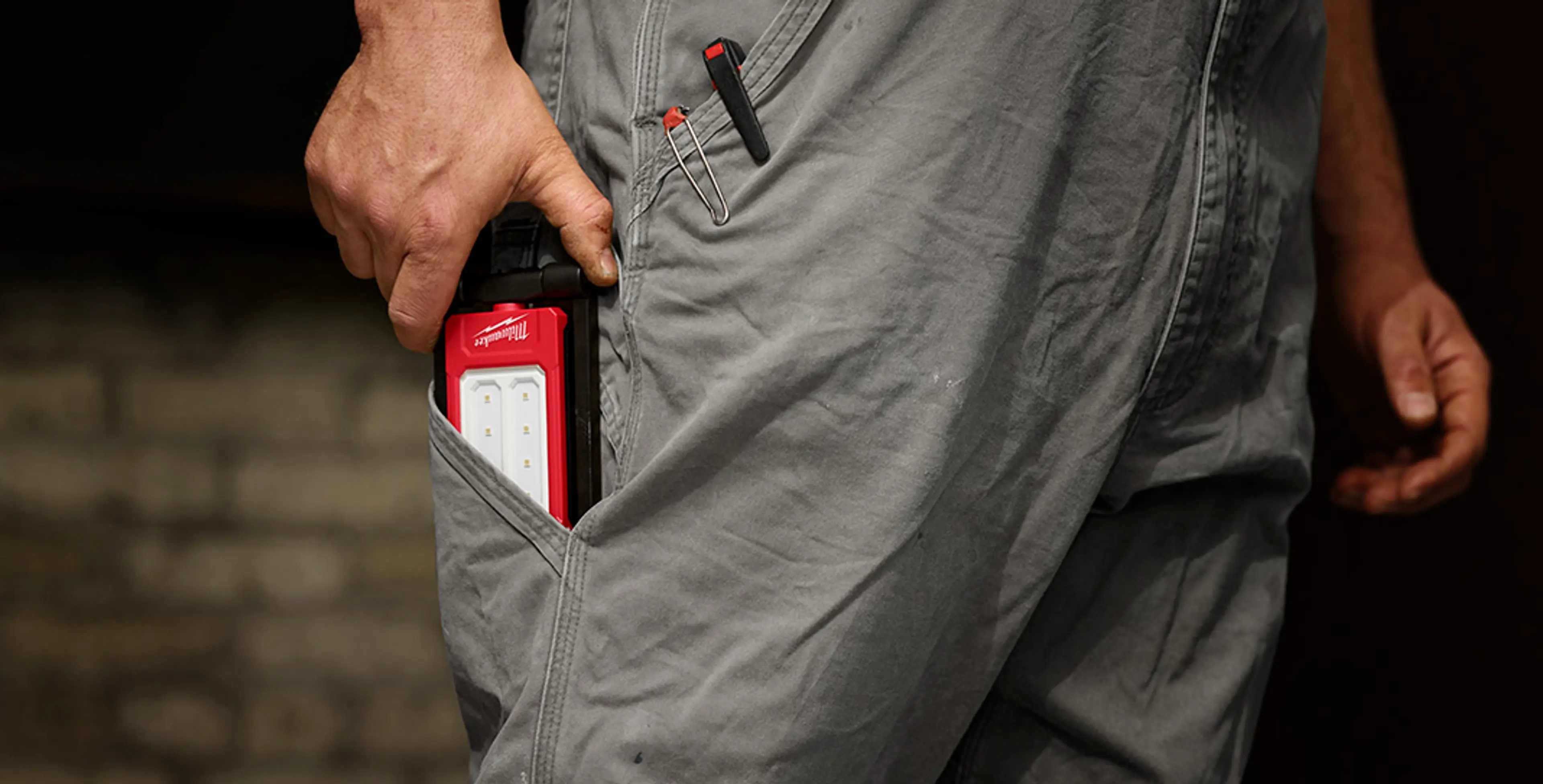 Person som putter IR FFL arbeidslampe fra MILWAUKEE® i lomma.