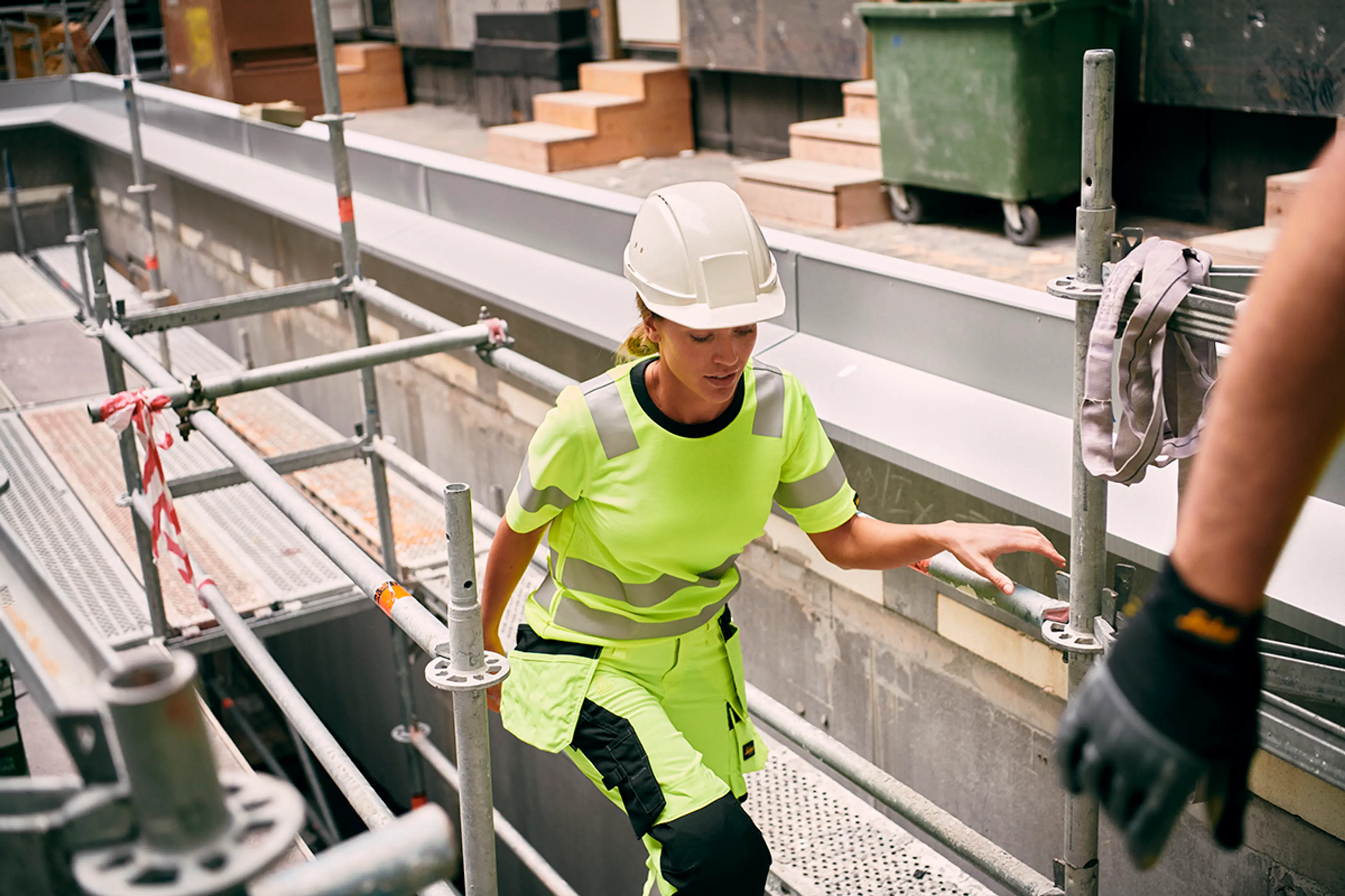 kvinnelig håndverker i high-vis arbeidsklær går opp et stillas