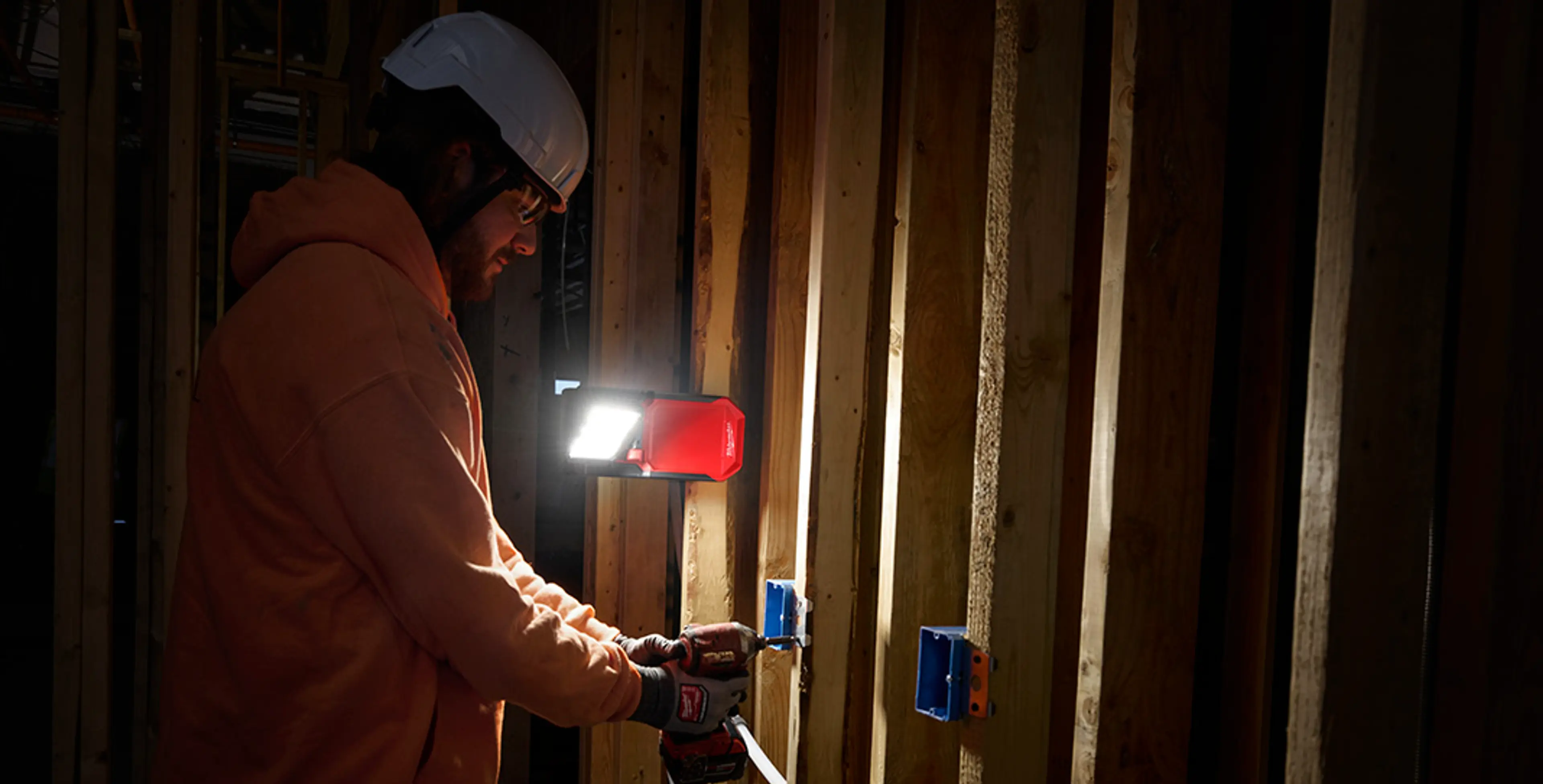 M18 PAL2 arbeidslampe fra MILWAUKEE® med klemmeåpning som er festet på reisverk.