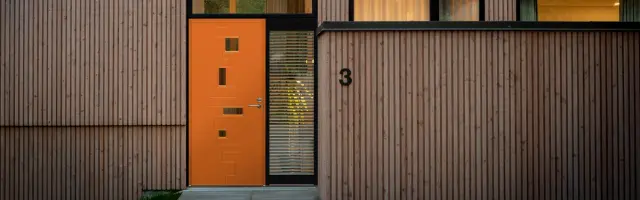 moderne hus med spilekledning og knalloransje ytterdør fra Swedoor
