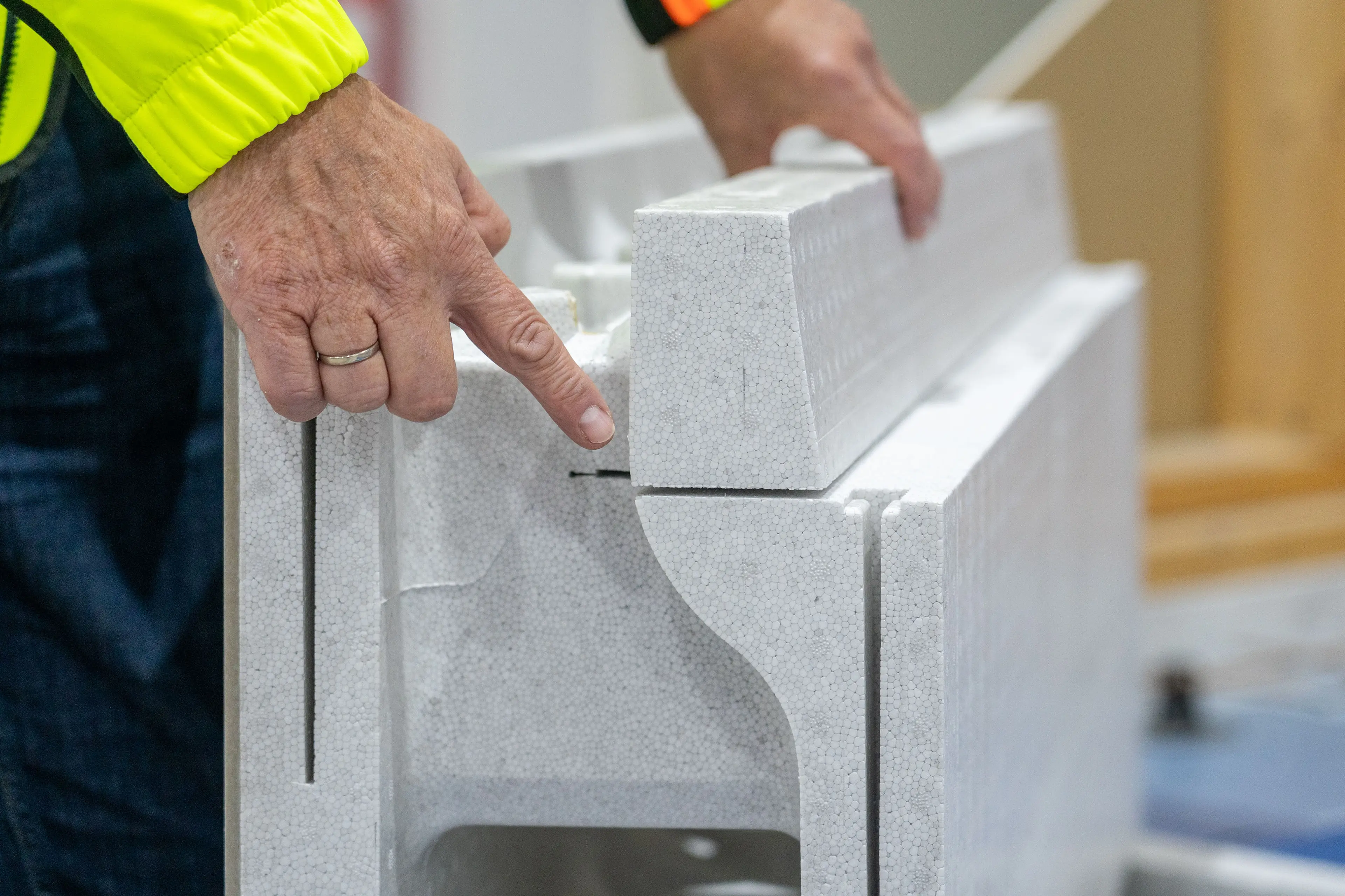 Mann i gul jakke peker på et spor for radonsikring i Jackon Ringmur RA-element