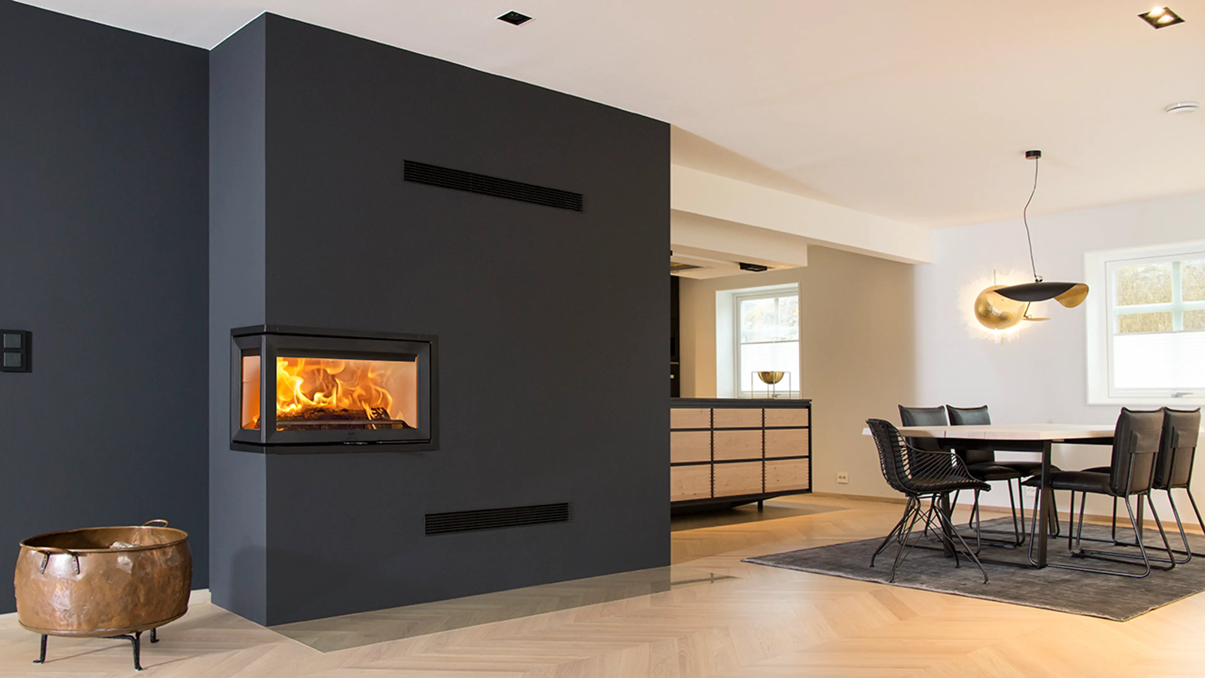 Mørk peis i åpen stue-kjøkken-løsning.