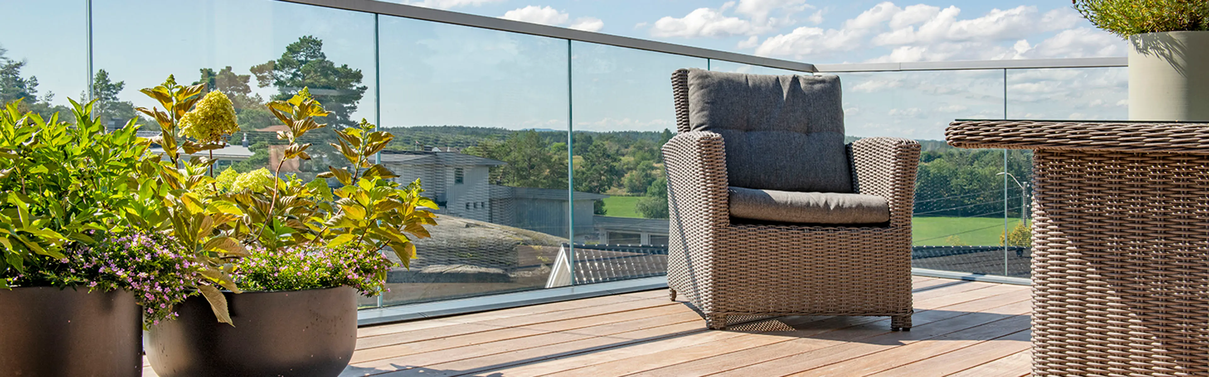 Glassrekkverk på terrasse med utsikt over fjord.