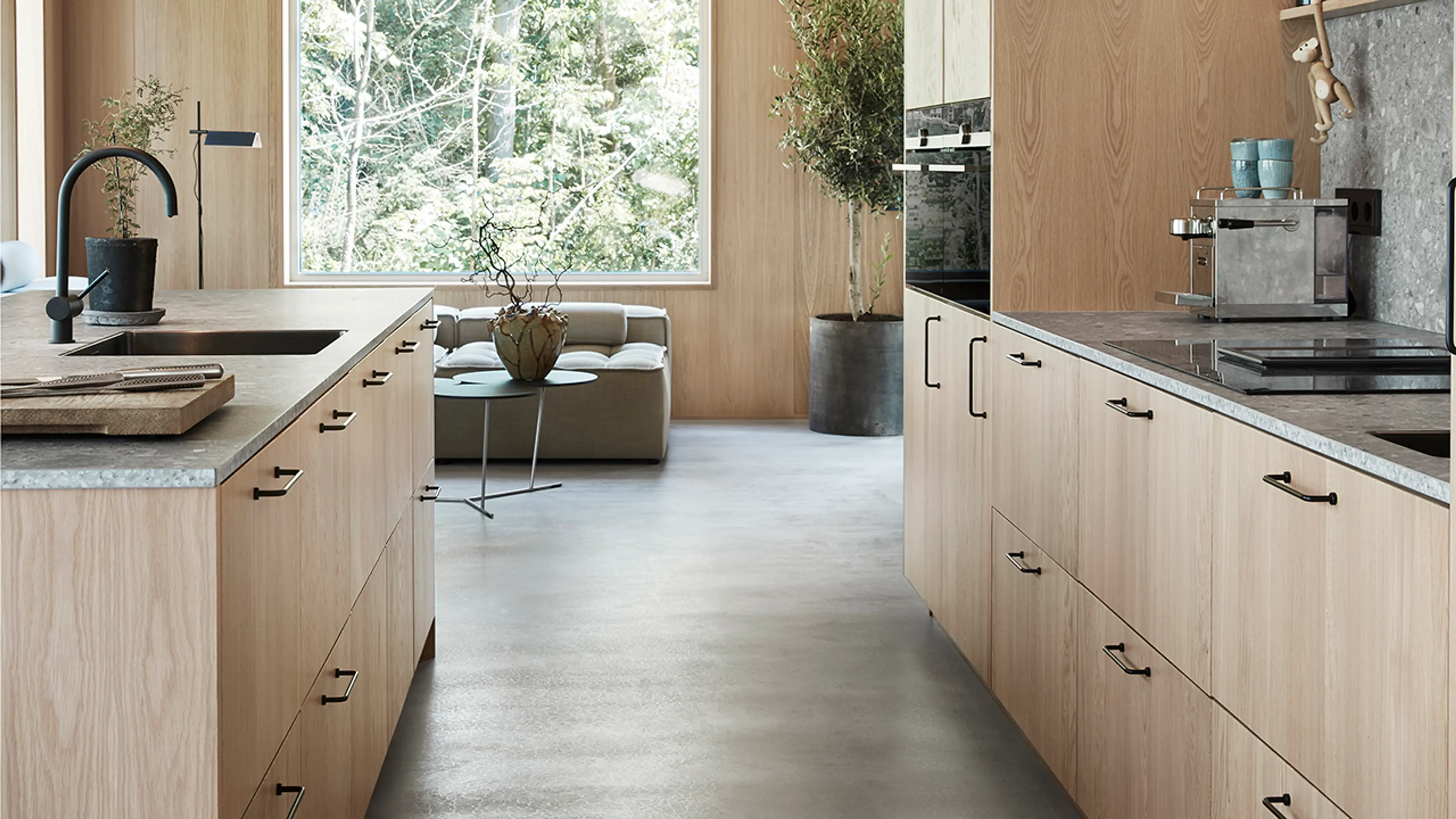 Hyttekjøkken i hvitpigmentert eik med benkeplate i grå stein i en moderne hytte i skogen.