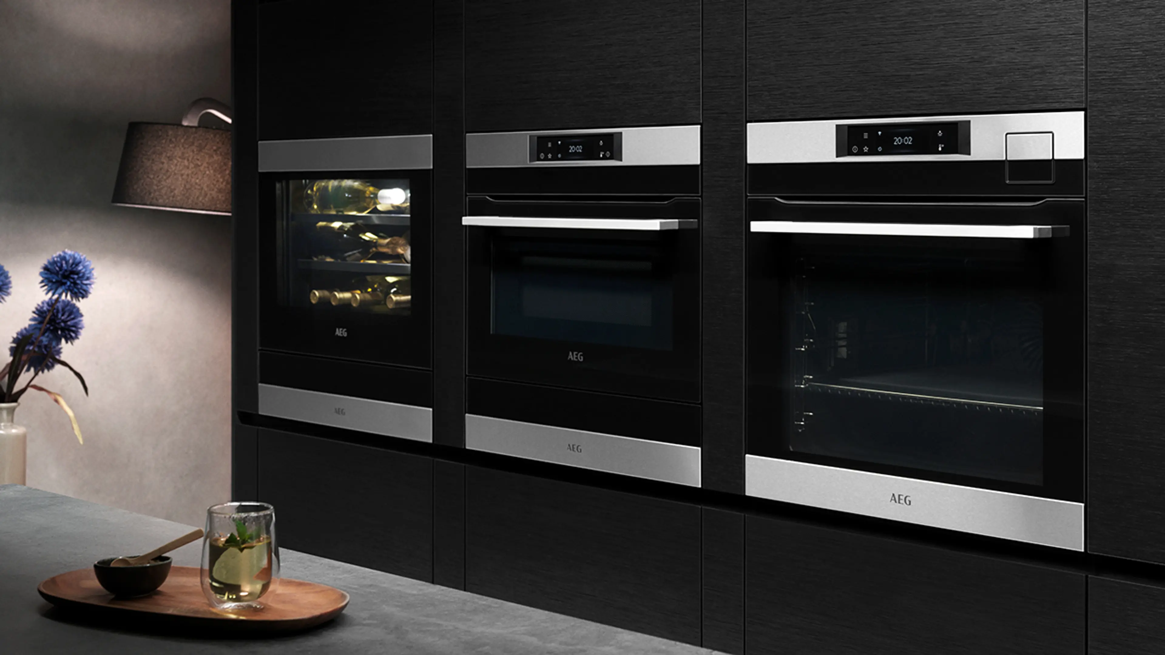 Nærbilde av dampovn og kombiovn i et svart kjøkken.