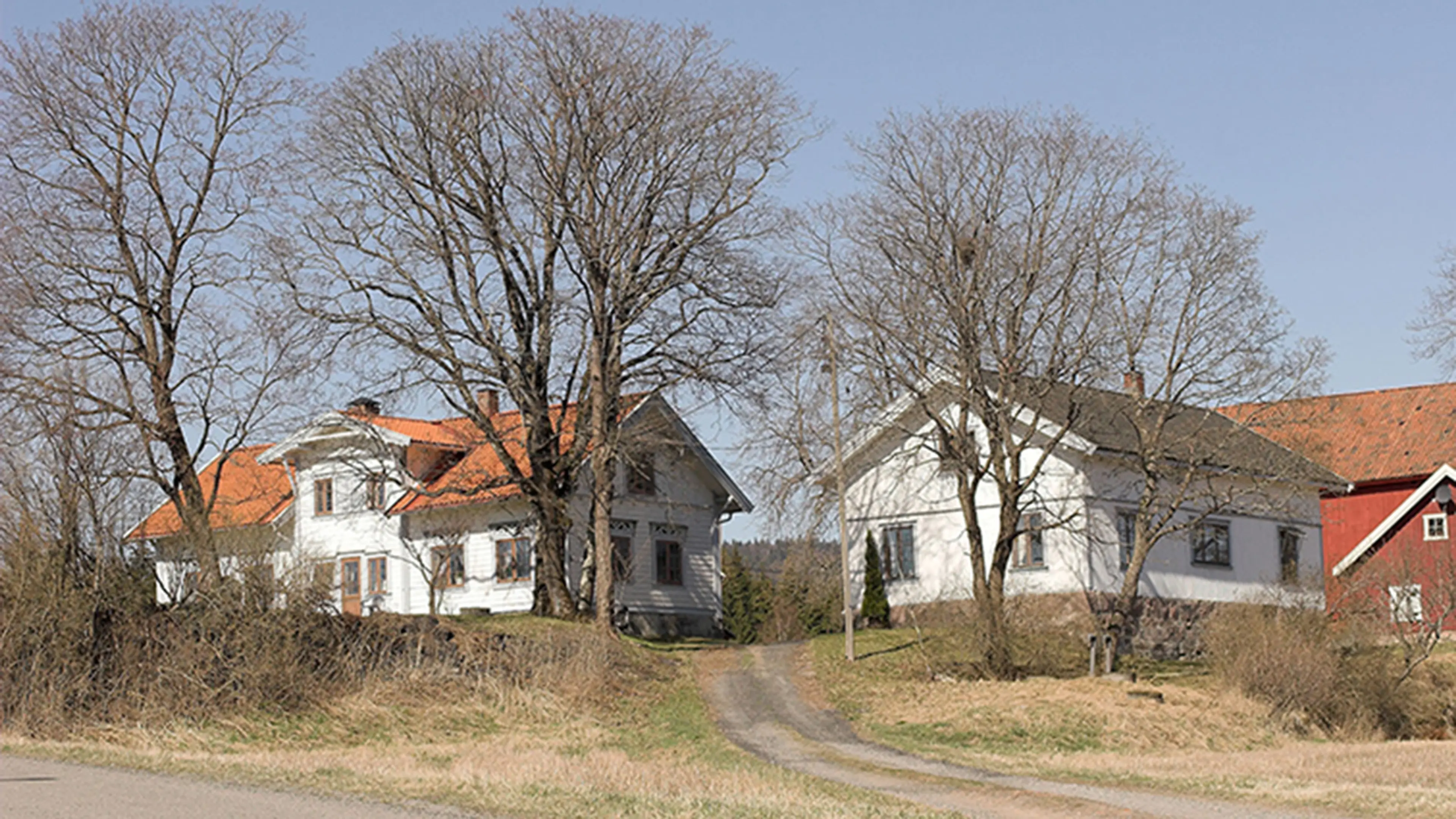 Gård med hvitt våningshus og rødt driftsbygg.