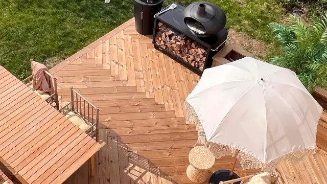 Terrasse sett ovenfra med pizzaovn, spisebord og parasoll.