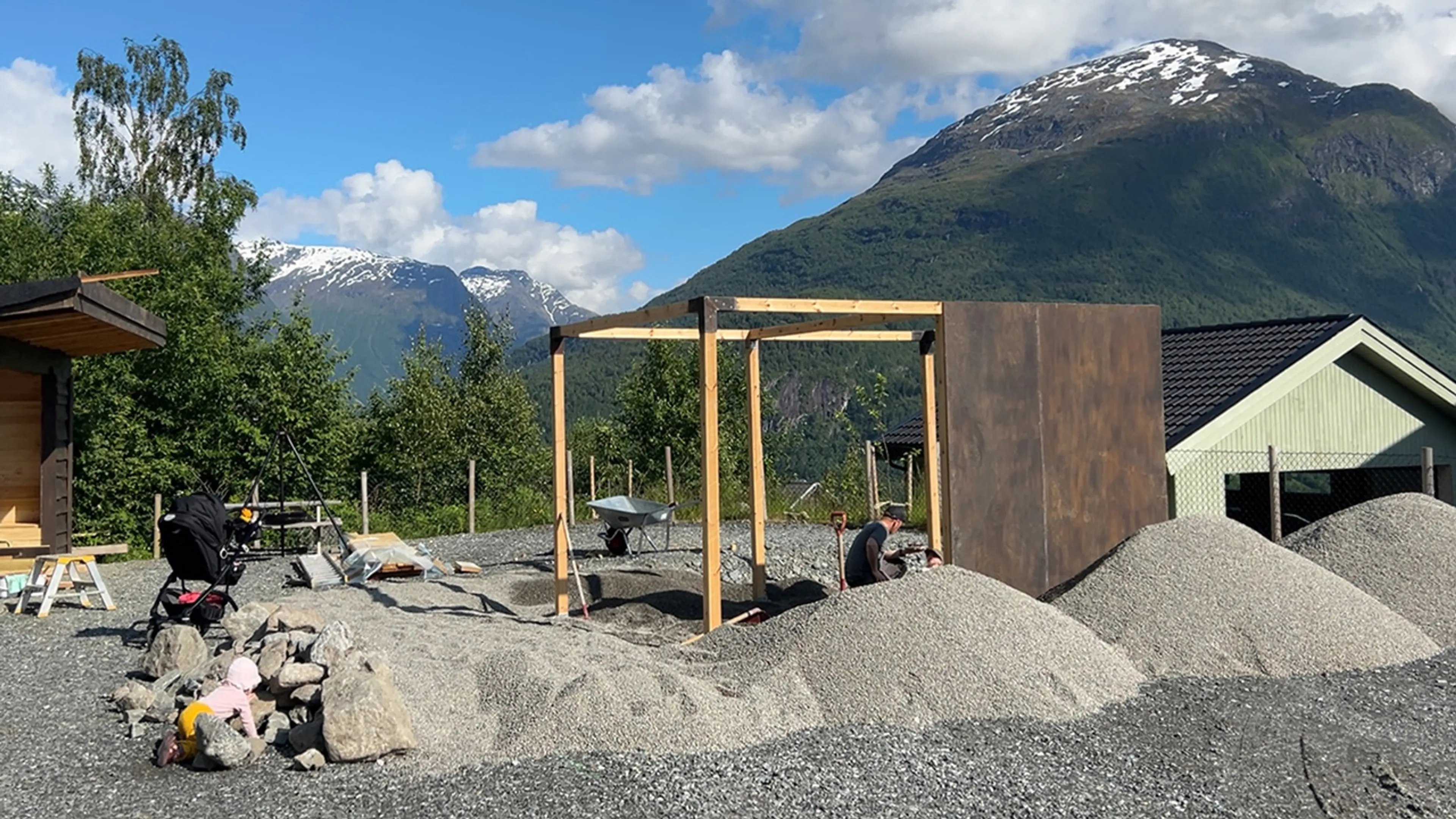 Mann som jobber med å grave vekk sand for å bygge klatrestativ.