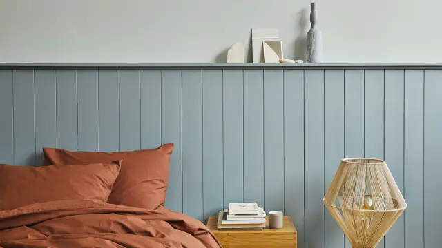 Blått soverom med blå sengegavl.