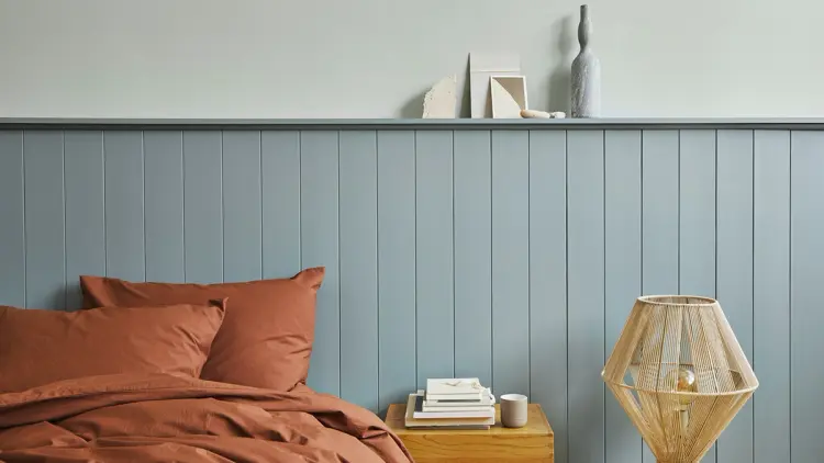 Blått soverom med blå sengegavl.