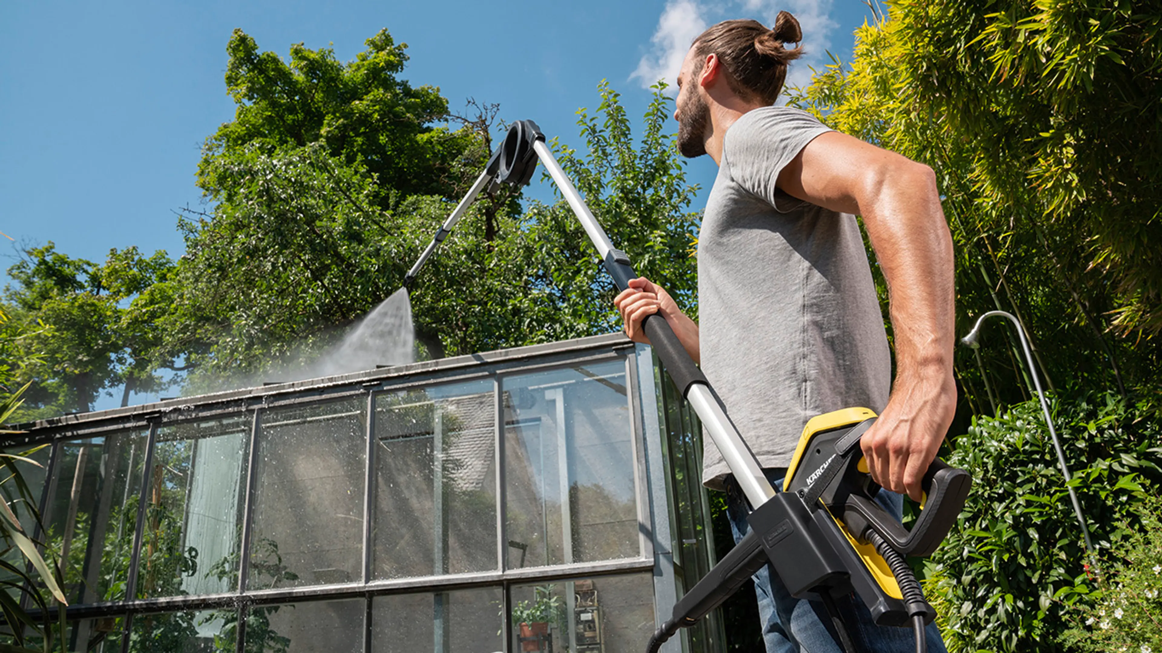 Mann som viser hvordan vaske vinduer ute på drivhus med høytrykkspyler.