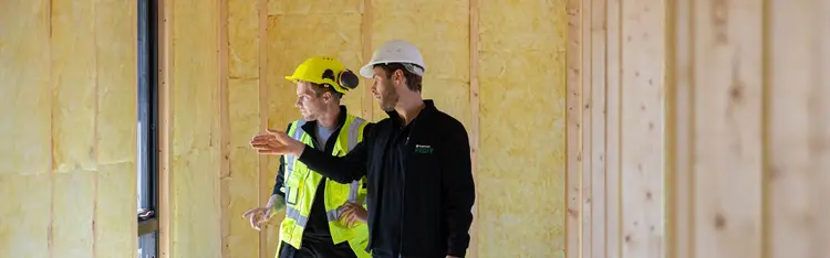 To mannlige håndverkere snakker sammen på en byggeplass
