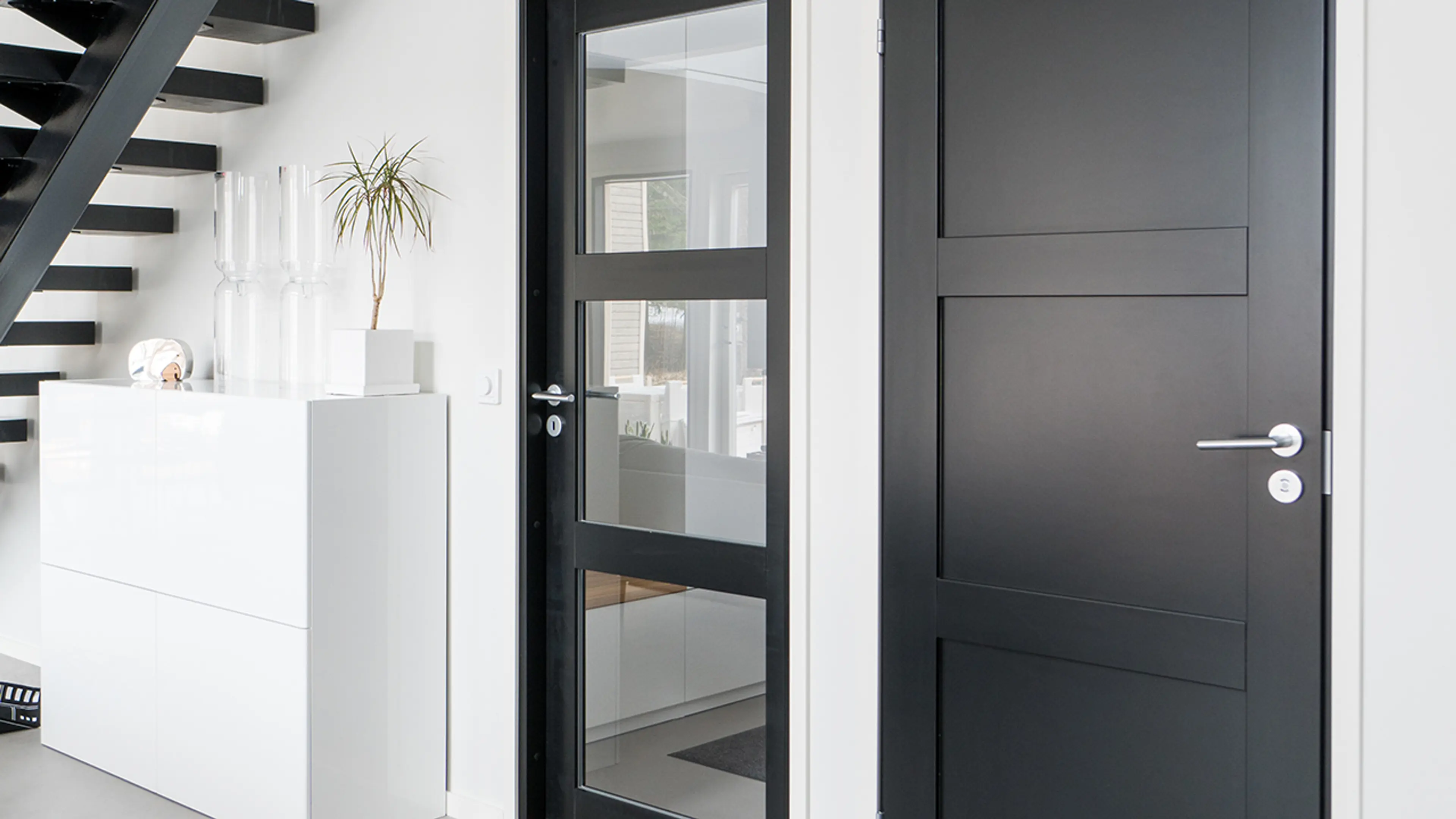 To sorte innerdører, en med glass og den andre er profilert.