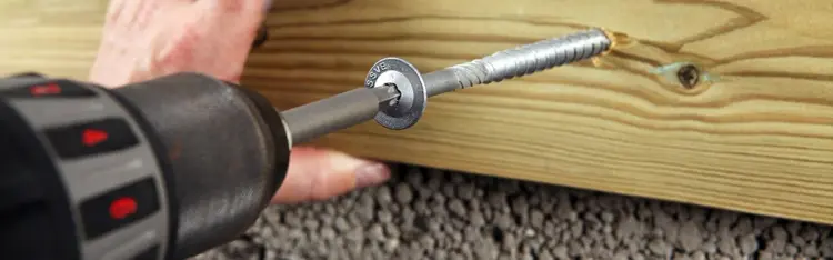 Mann skrur inn en betongskrue fra Essve med drill.