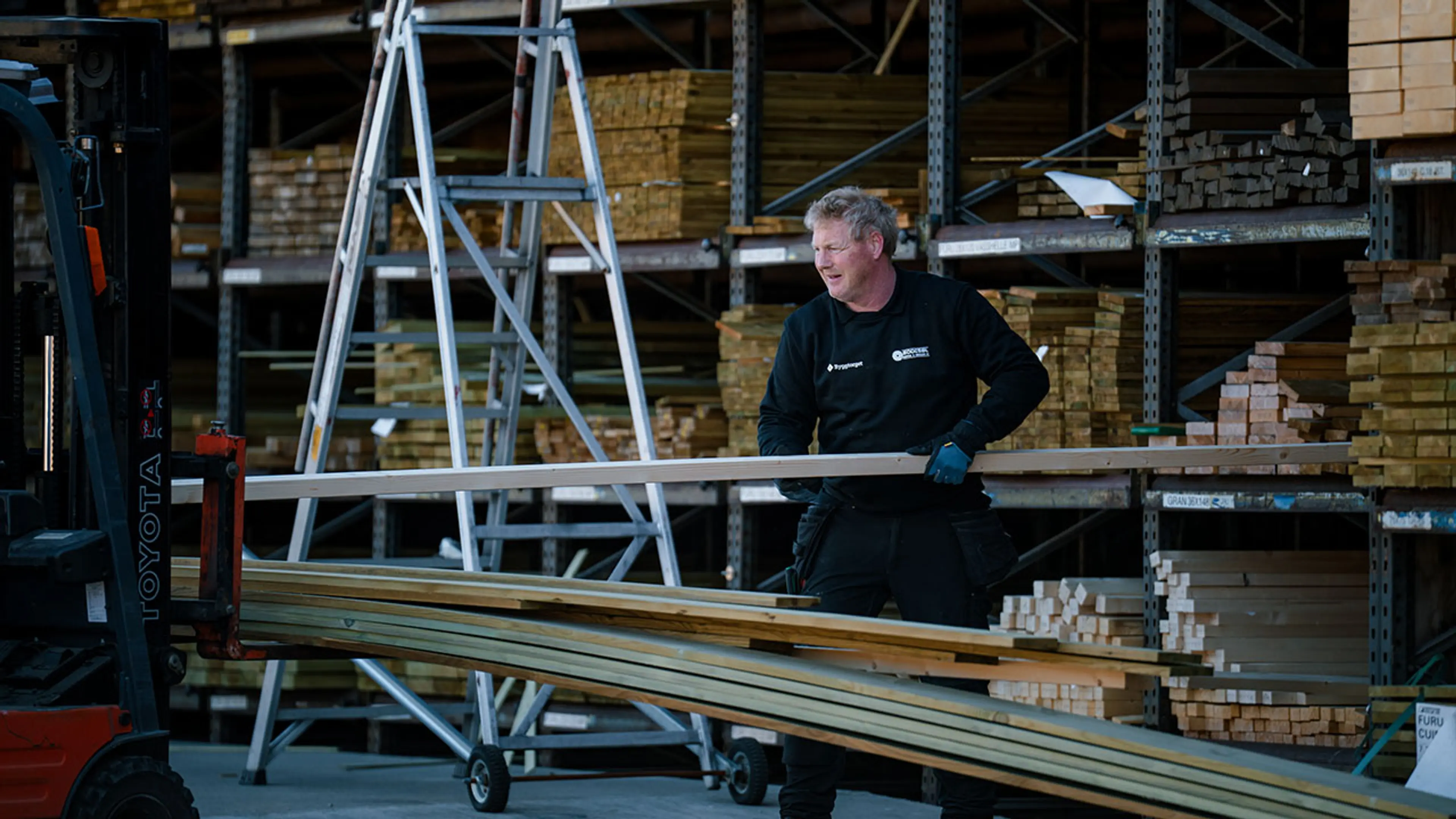 Byggtorget ansatt bærer terrassebord til kunde.