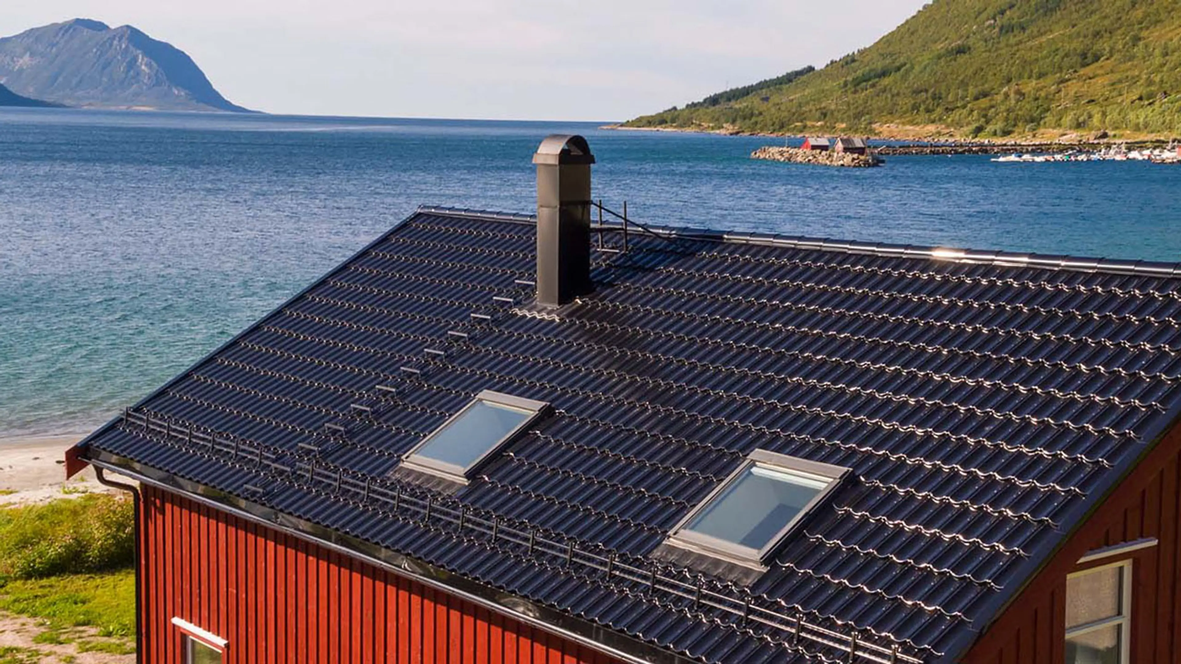 Rødt hus ved sjøen med Isola Powertekk tak.