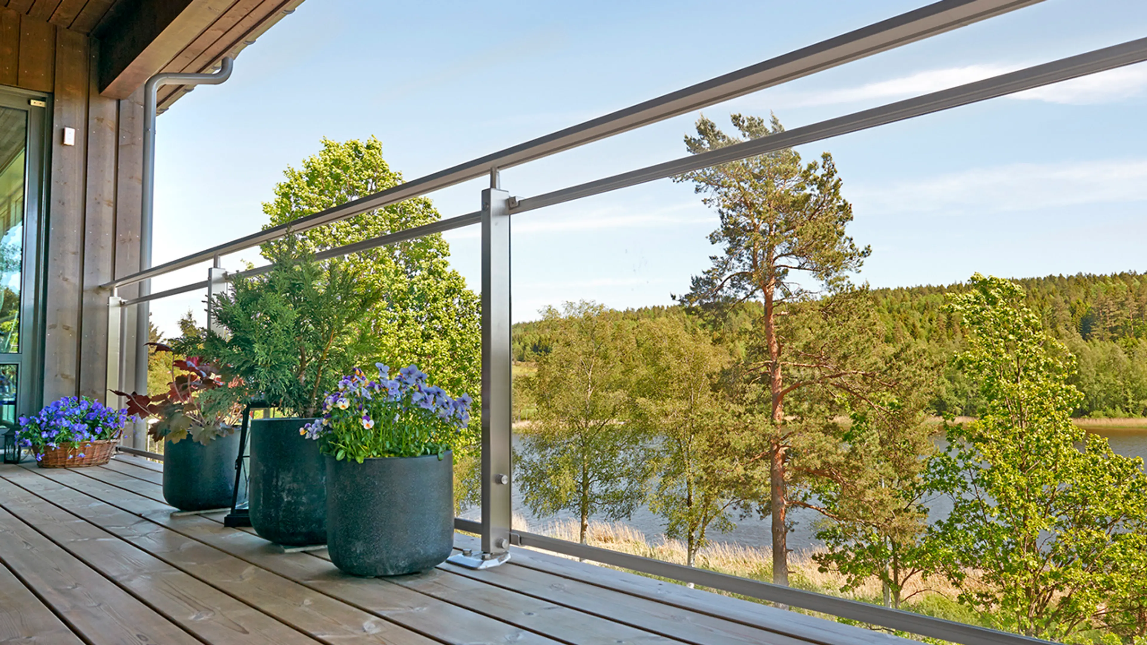 Det finner mange terrasse rekkverk typer. Her ser du glassrekkverk på terrasse som bevarer utsikten mot skogen og vannet.