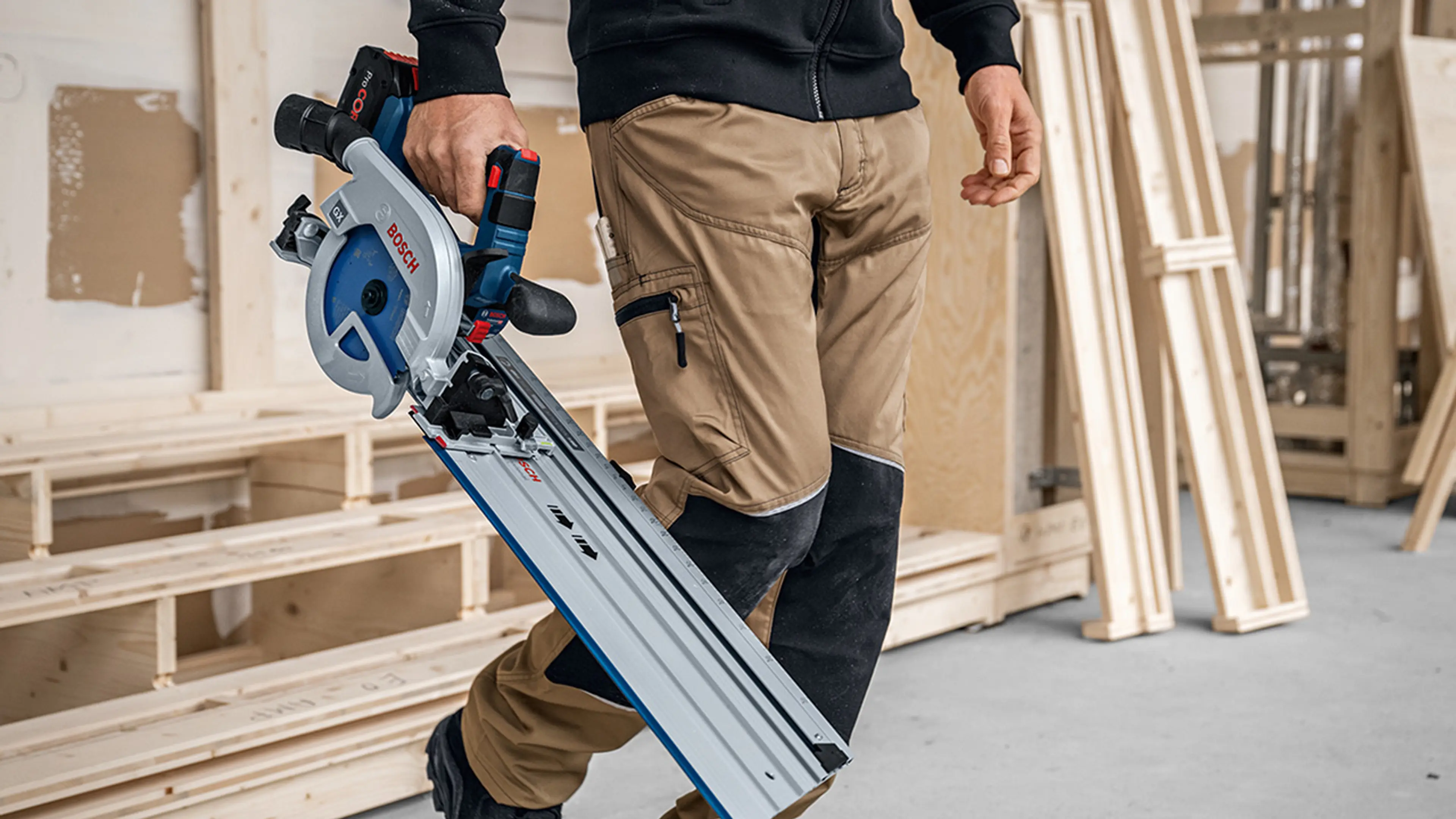 Mann på byggeplass som bærer en blå stikksag.