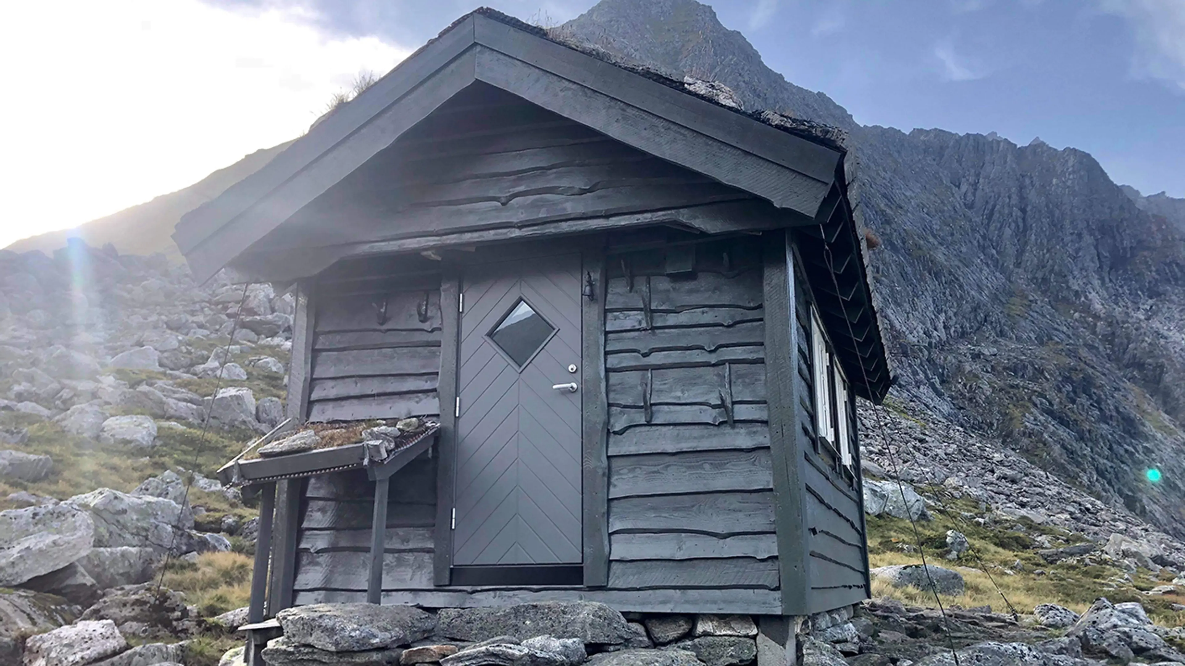 Grå ytterdør på en liten hytte i fjellheimen.