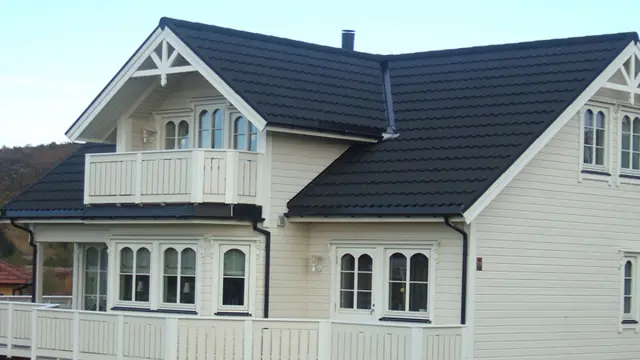 Lysmalt hus med sorte takplater.