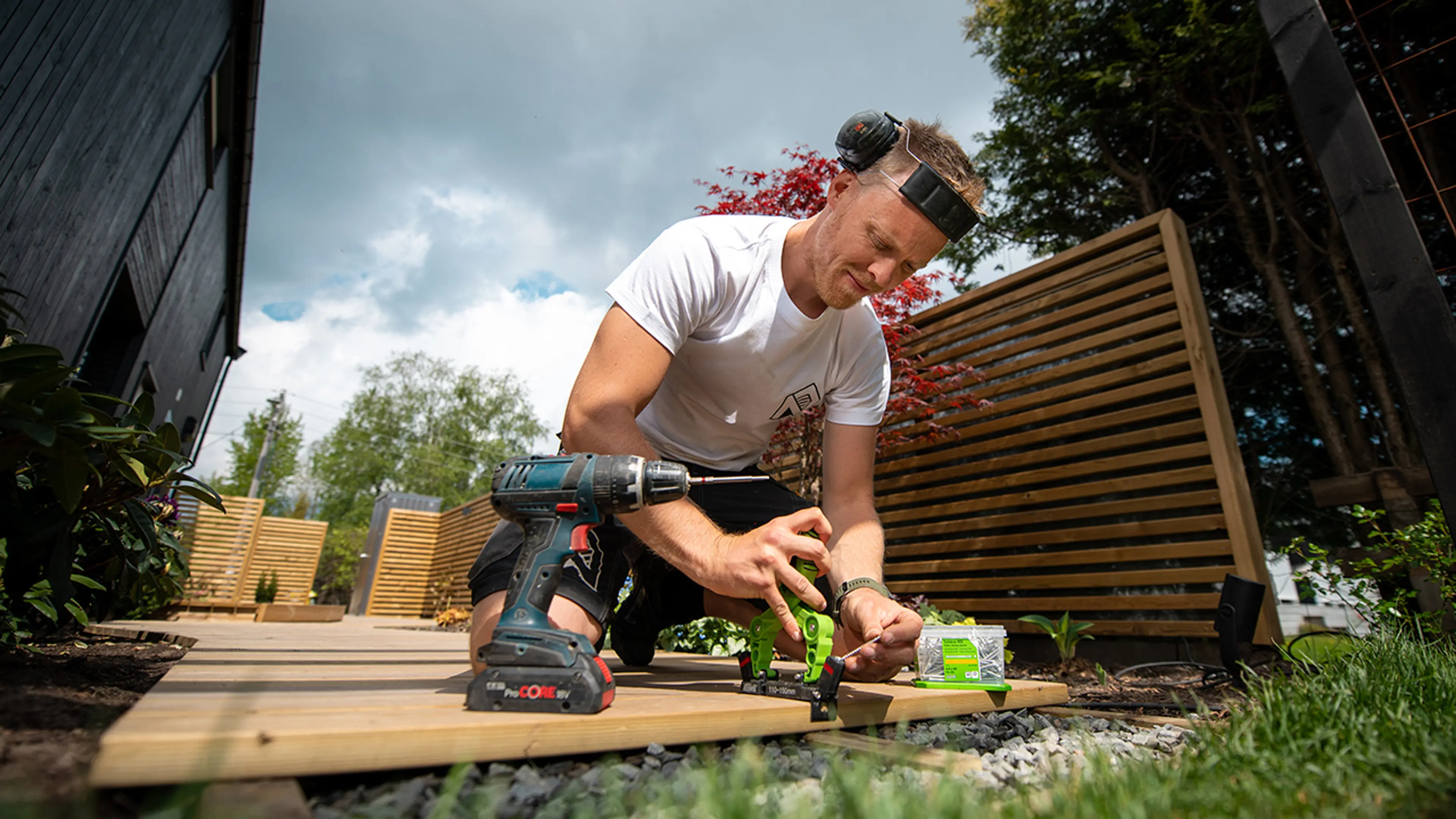 Mann som bygger terrasse med drill og skjult innfesting.