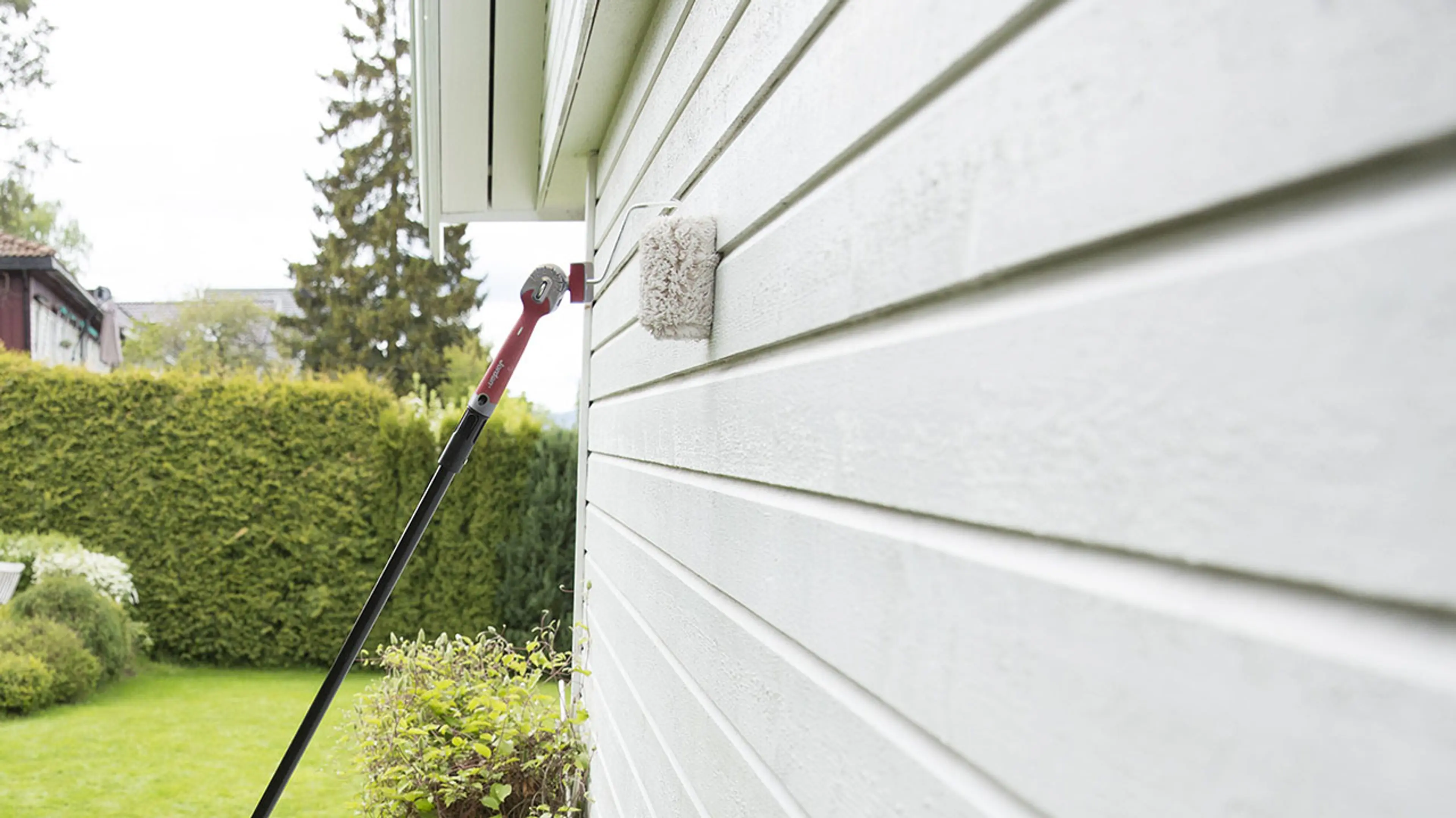 Hus som males hvitt med rulle og forlengerskaft.