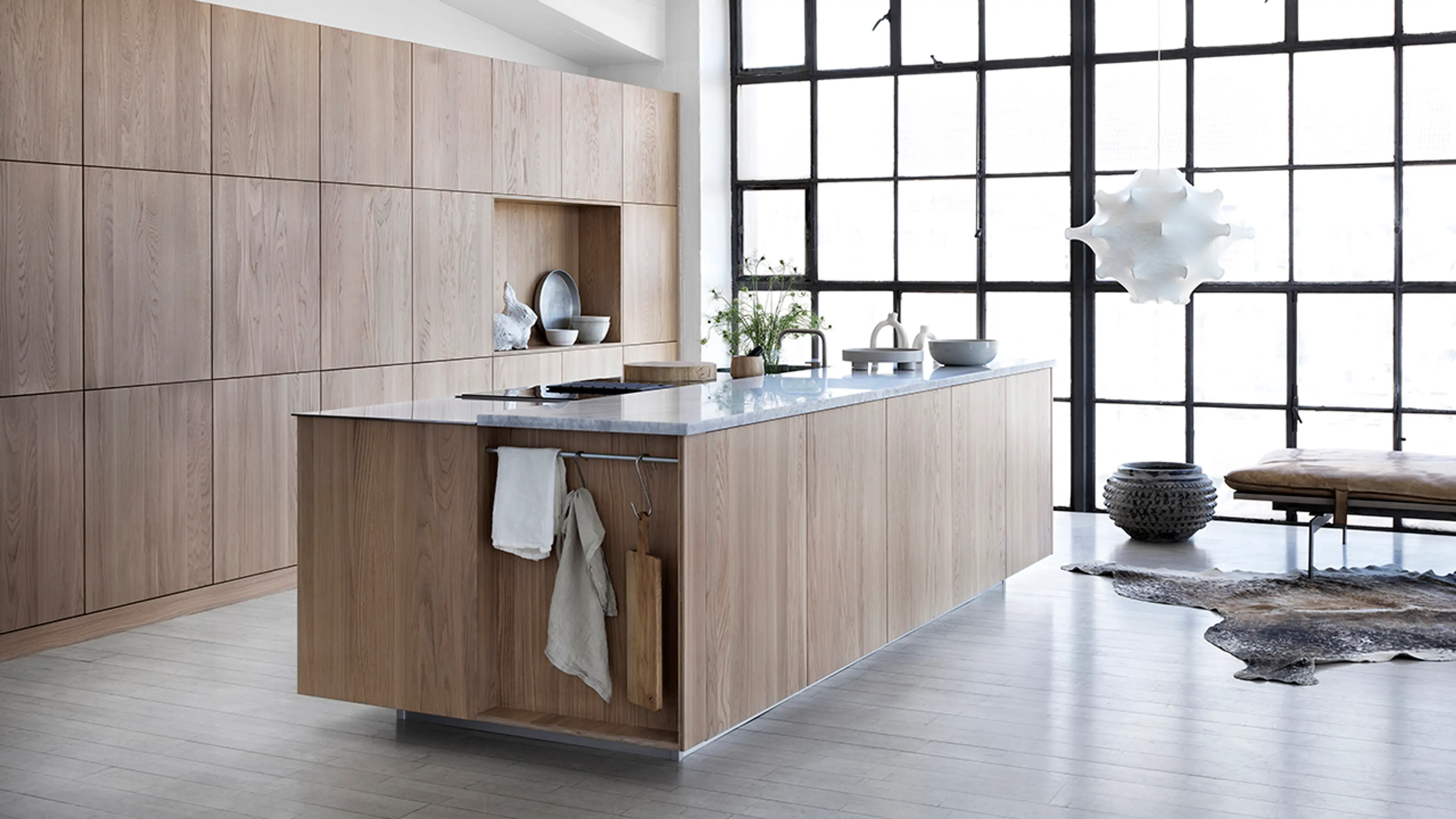 Kjøkken med høyskap på en hel vegg og stor kjøkkenøy.