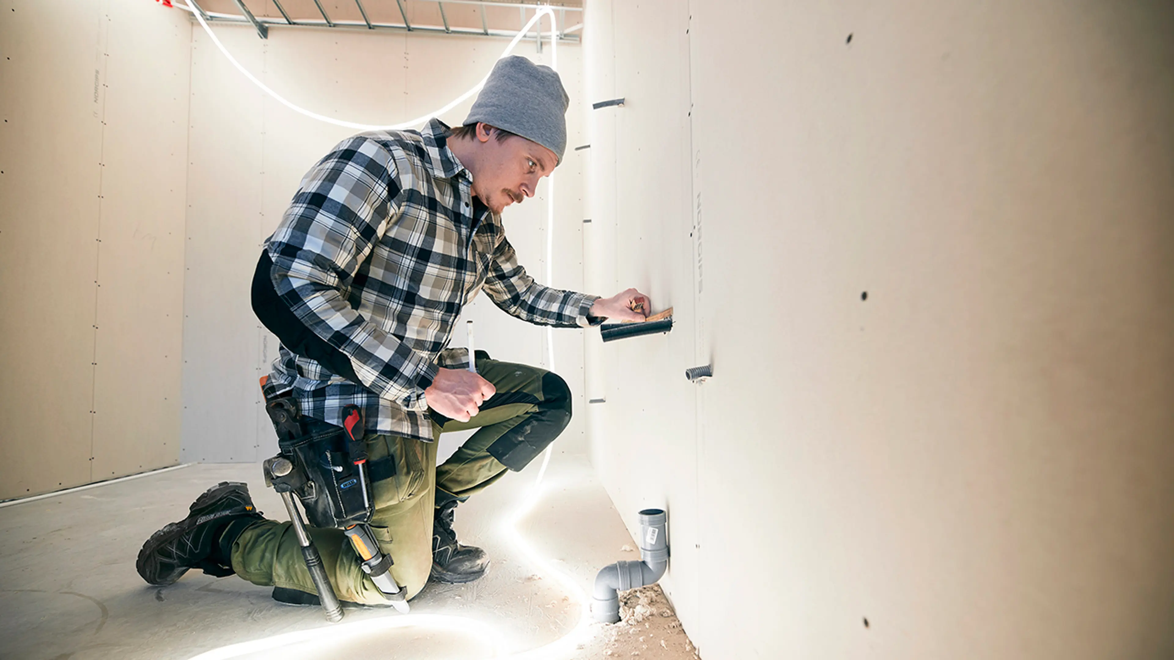 Håndverker som jobber innendørs med LED-lyslist som arbeidslampe.