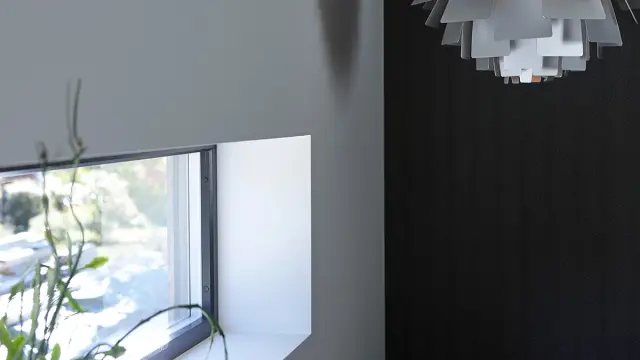 Nærbilde av listefritt vindu i rom med kontrastvegg.